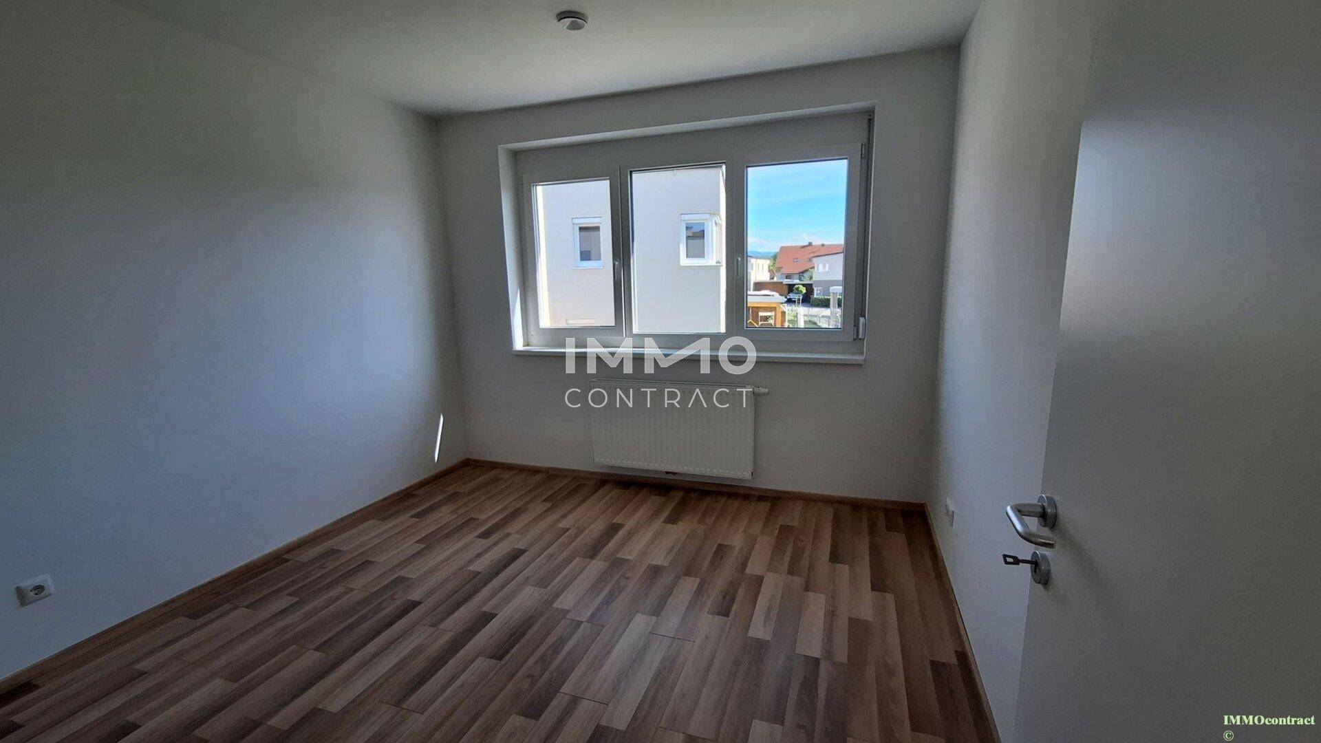 Komfortables Schlafzimmer mit Laminatboden und großem Fenster für viel Licht.