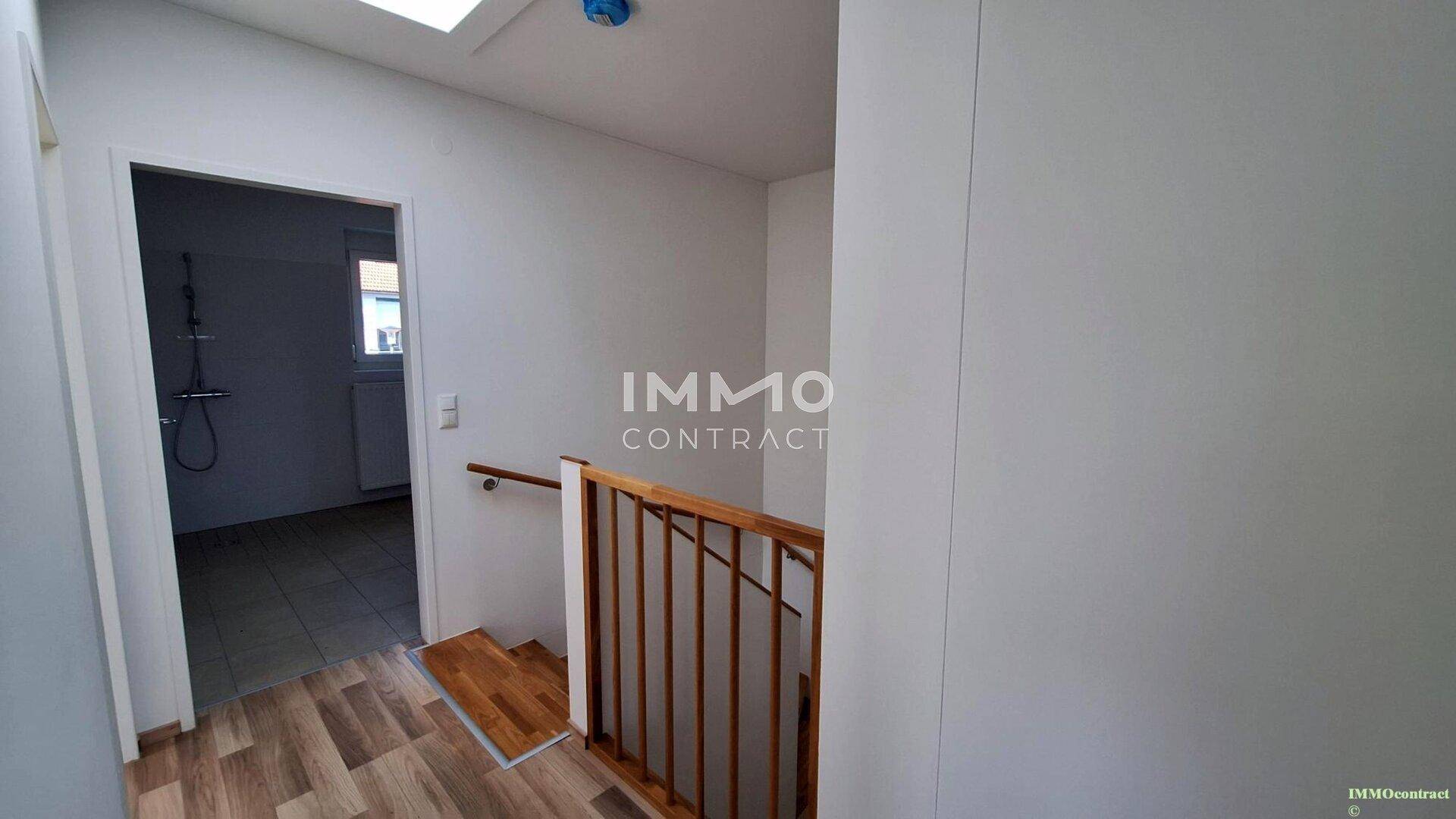 Flur im Obergeschoss mit Holzgeländer und Zugang zum Badezimmer.