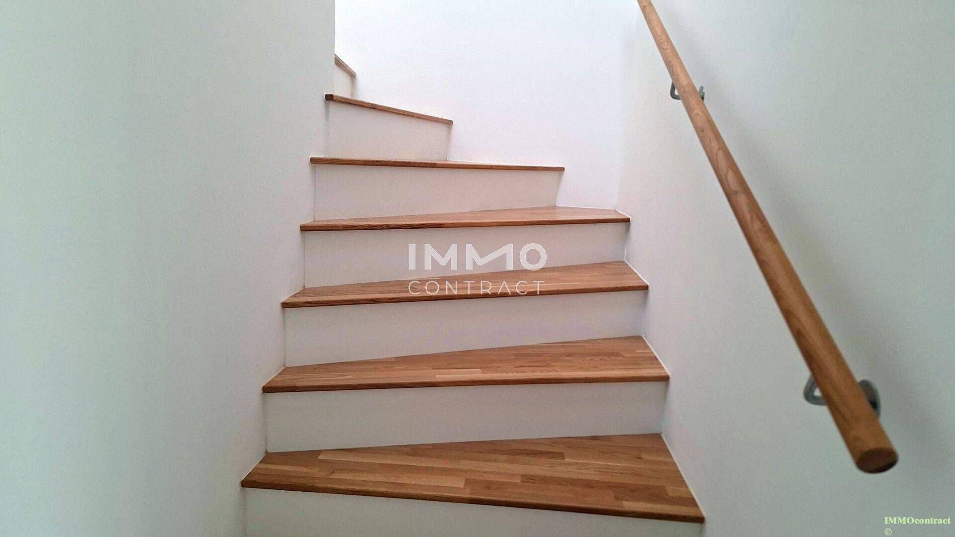Holztreppe mit hellem Geländer verbindet die Stockwerke des Hauses in modernem Design.