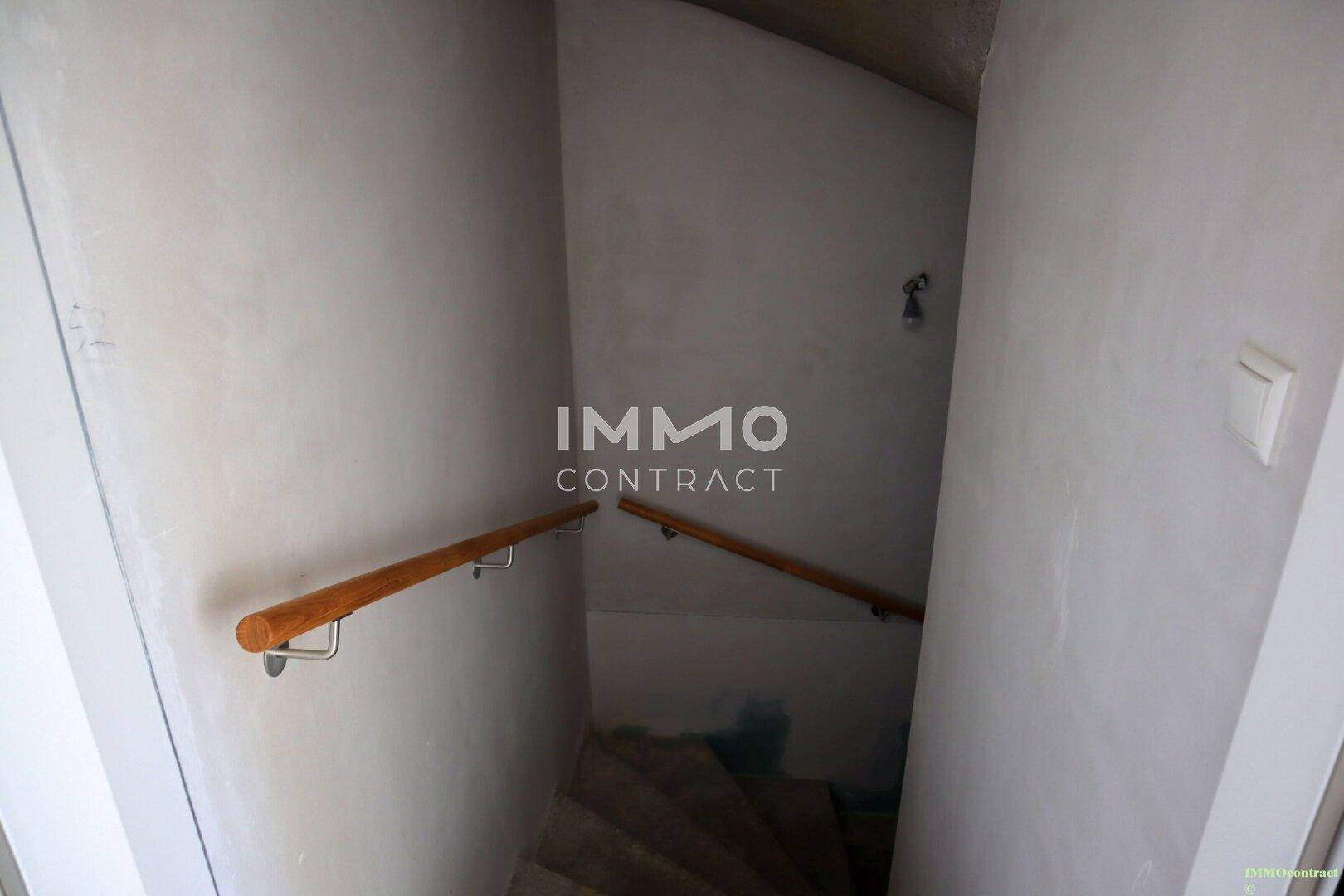 Treppe führt in den Kellerbereich, mit schlichtem Holzgeländer.