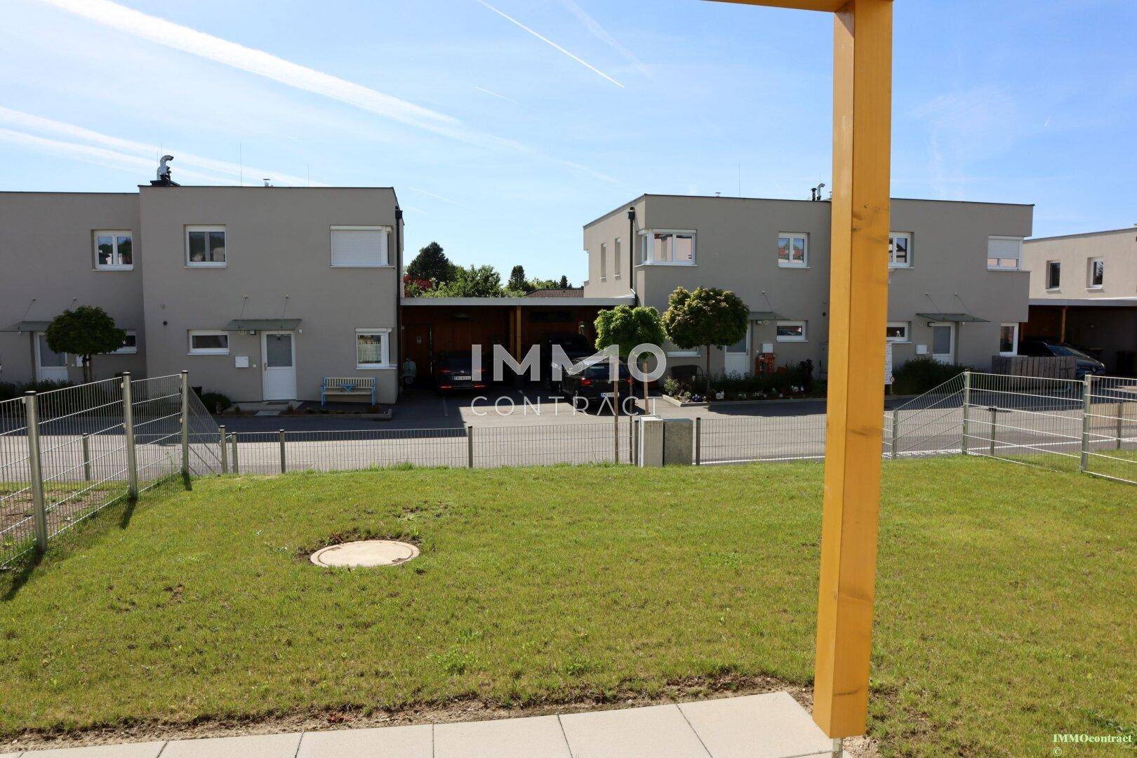Blick über einen gepflegten Rasen auf weitere moderne Reihenhäuser in der Siedlung.