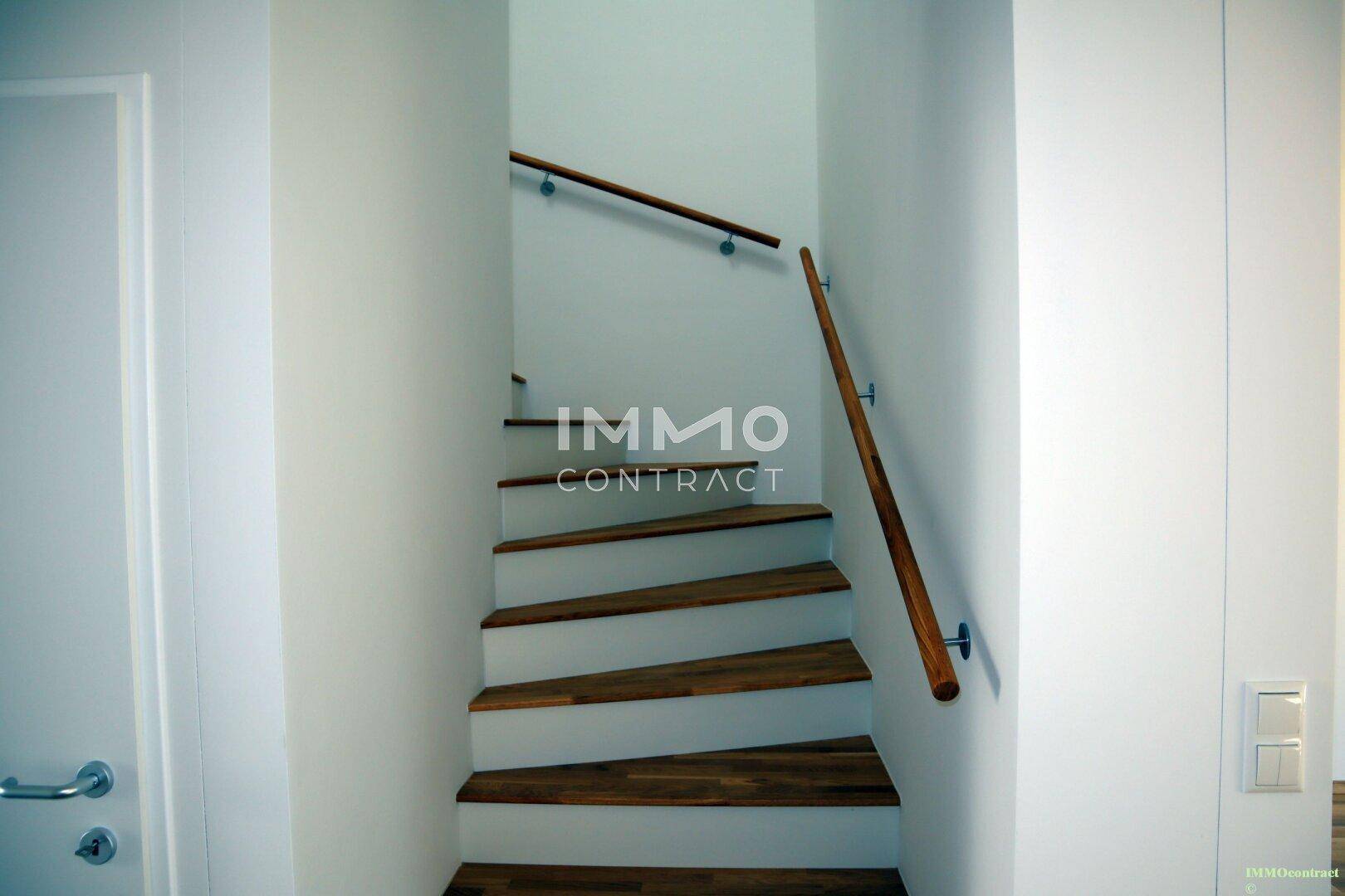 Moderne Holztreppe mit schlichtem Geländer, die in die obere Etage führt.