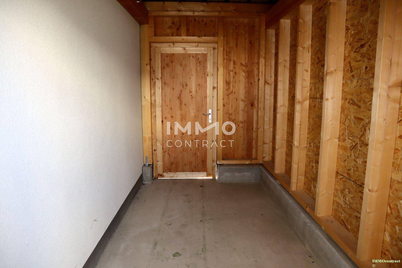 Abstellraum mit Holzwänden und Betonsockel, ideal für Gartengeräte oder Fahrräder.