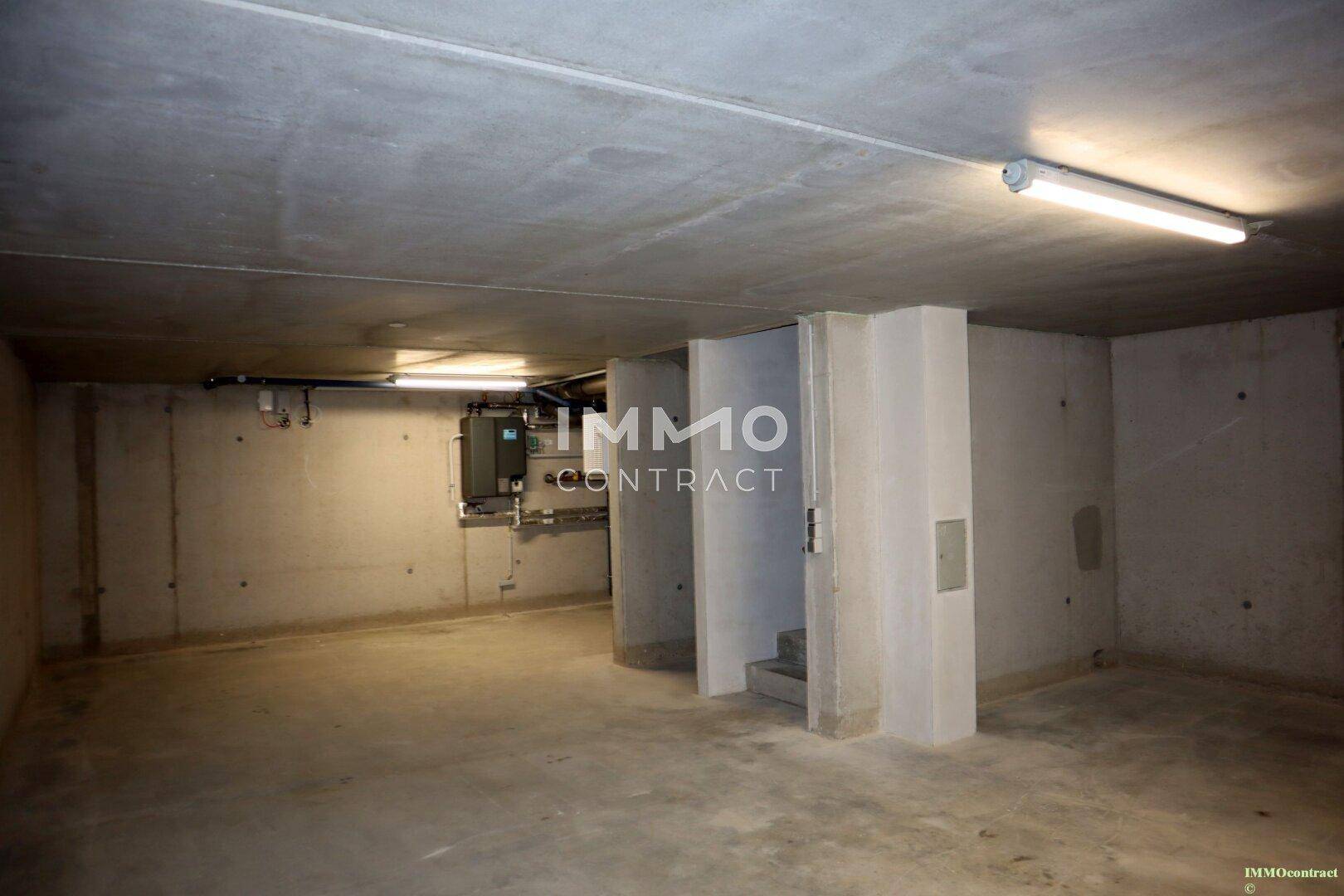 Geräumiger Kellerraum mit Betonboden und sichtbaren Versorgungsleitungen.
