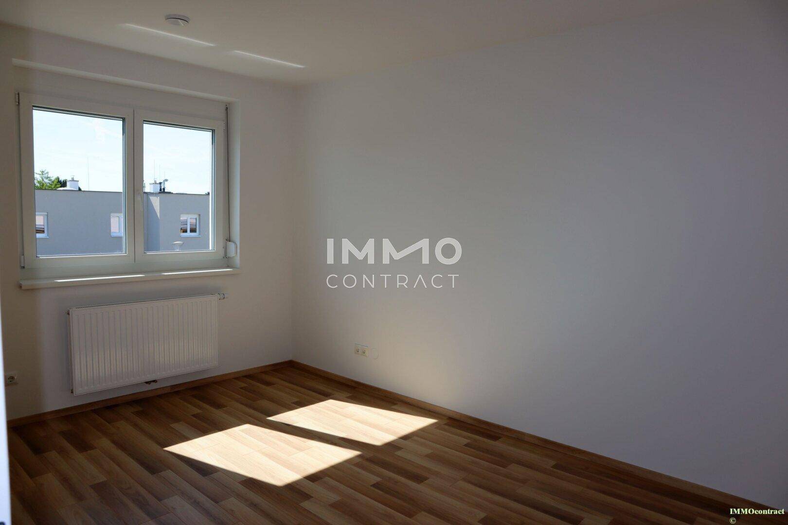 Geräumiges Schlafzimmer mit Holzboden und viel Tageslicht durch das große Fenster.