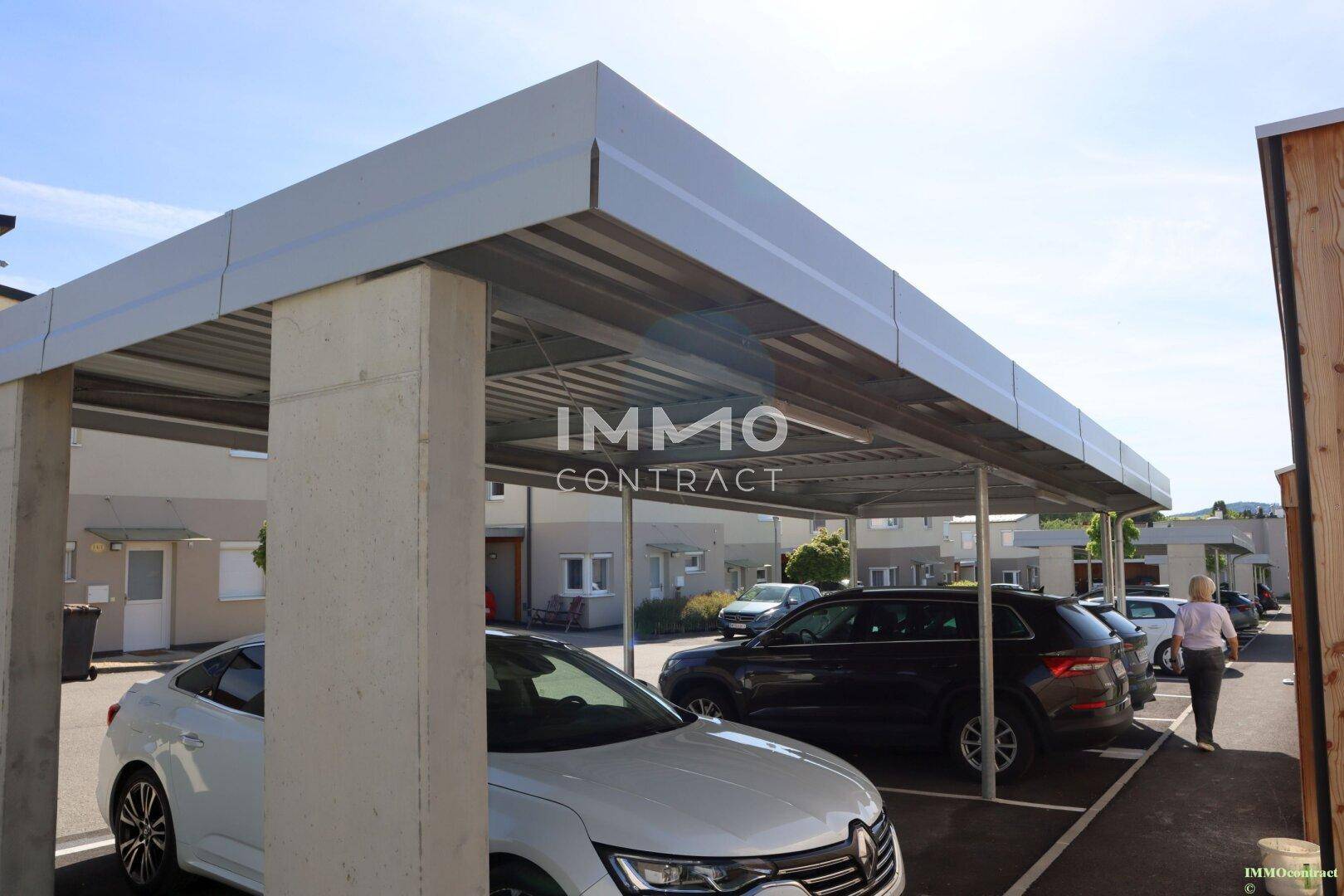 Überdachter Carport-Bereich mit mehreren Stellplätzen für Fahrzeuge in der Siedlung.