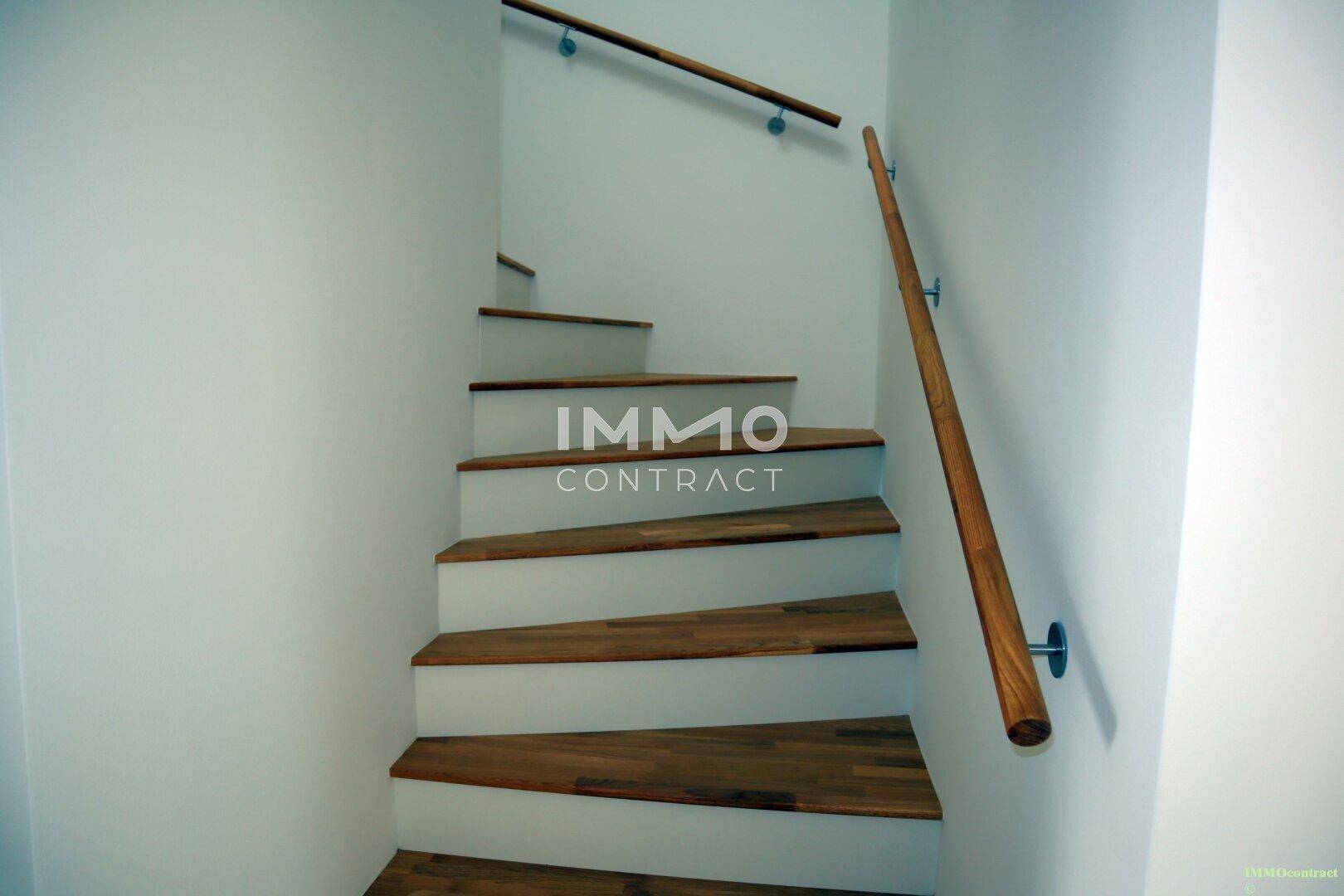 Moderne Holztreppe mit Geländer, die die verschiedenen Etagen des Hauses verbindet.