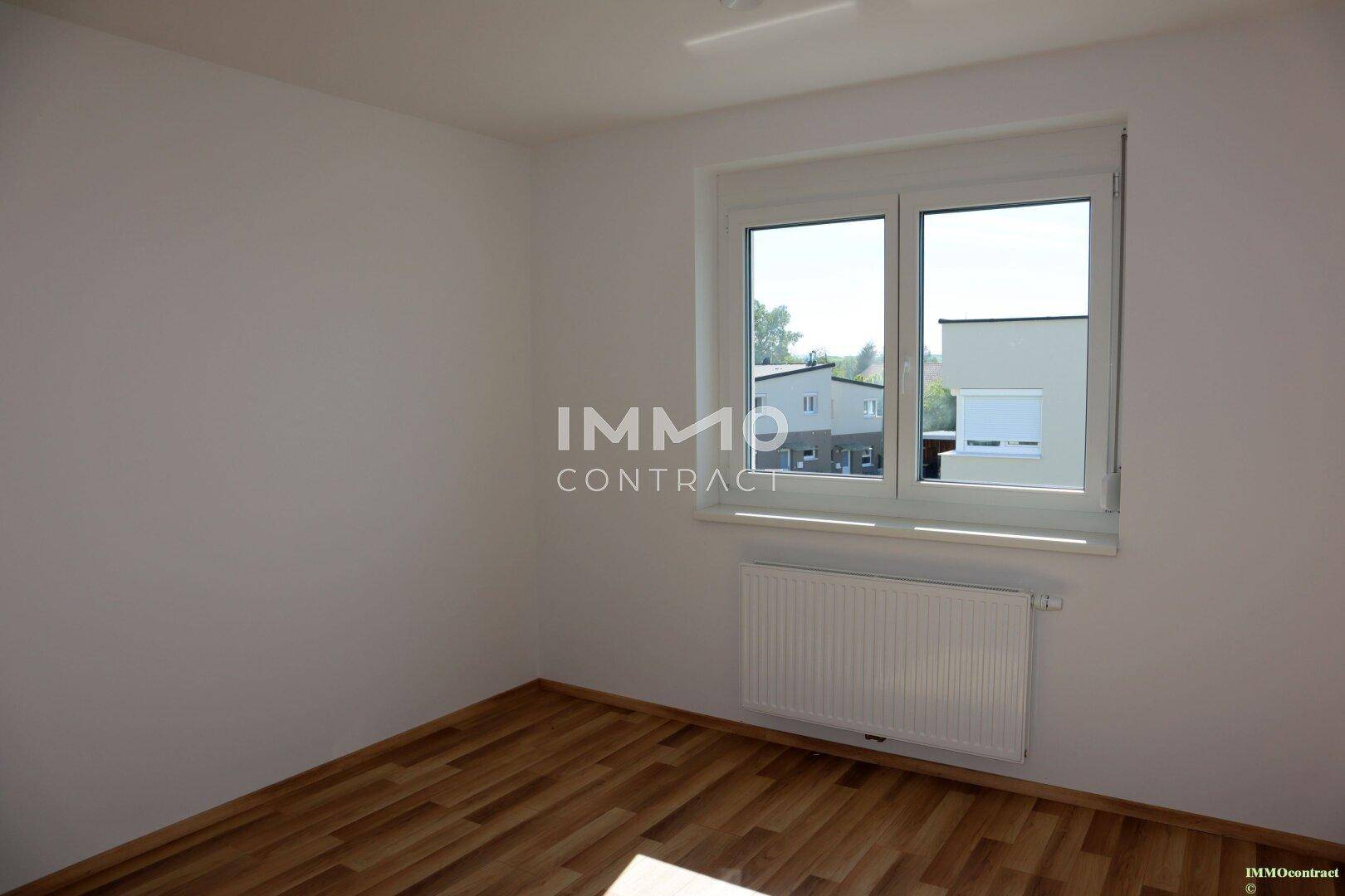 Geräumiges Schlafzimmer mit großem Fenster und Heizkörper, bereit zur Einrichtung.