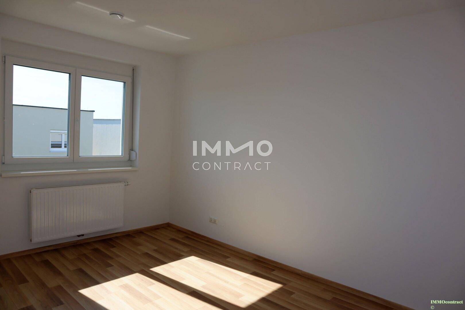Geräumiges Schlafzimmer mit Laminatboden und viel Tageslicht durch das Fenster.