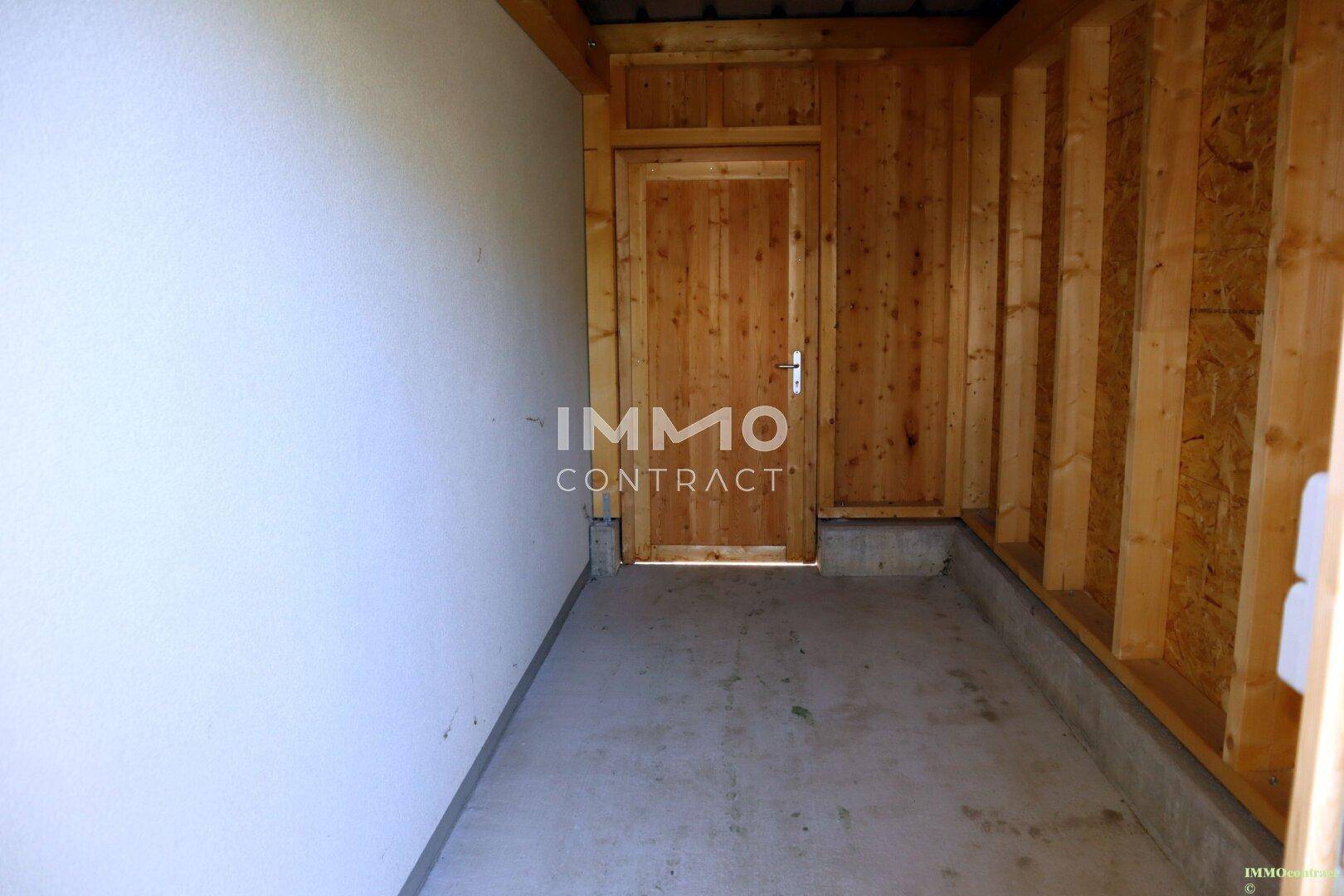 Abstellraum mit Holzwänden und Betonsockel, ideal für Gartengeräte oder Fahrräder.