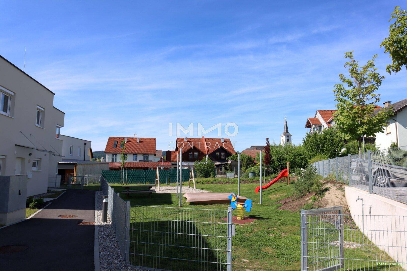 Kinderspielplatz in der Wohnsiedlung mit Rutsche und Schaukeln.