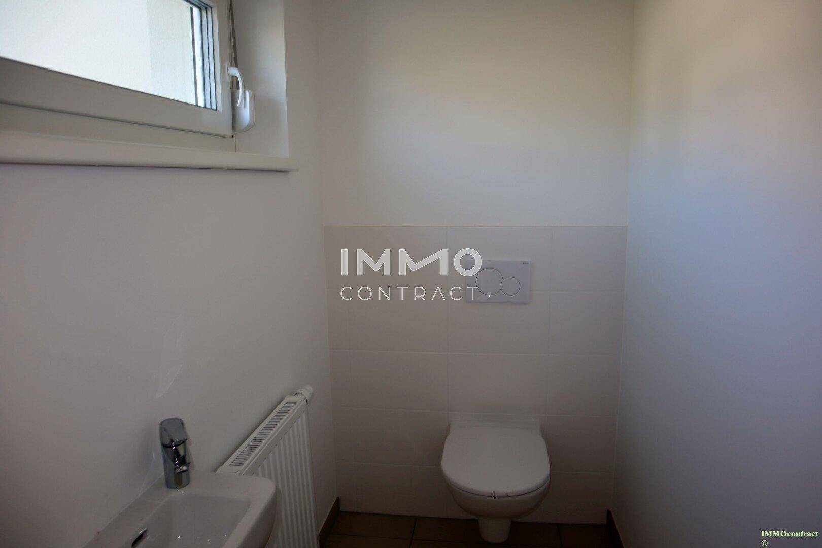 Gäste-WC mit wandhängender Toilette, kleinem Waschbecken und Fenster.