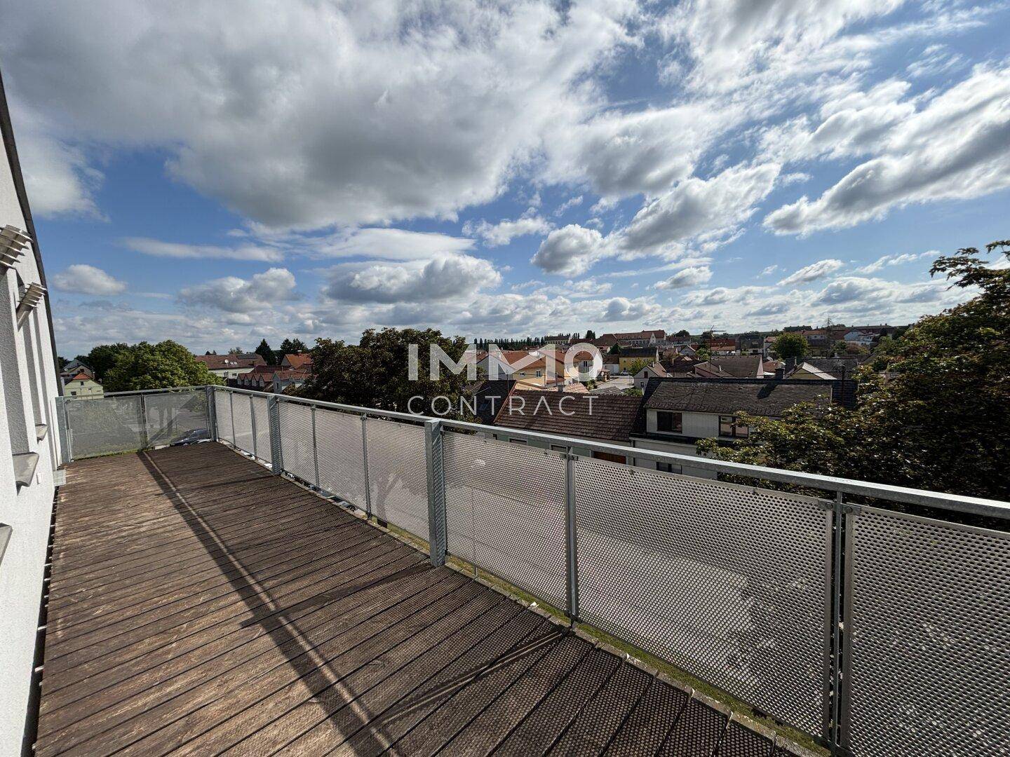 Geräumiger Balkon mit Holzboden und Metallgeländer, bietet einen weiten Blick über die Umgebung.