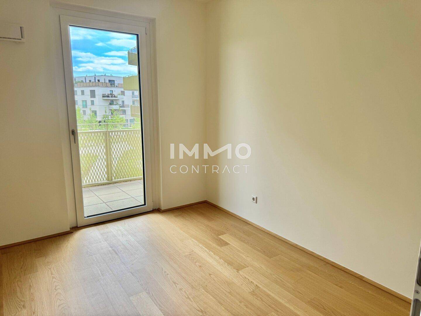 Helles Zimmer mit Parkettboden und direktem Zugang zum Außenbereich, ideal als Schlafzimmer oder Büro.