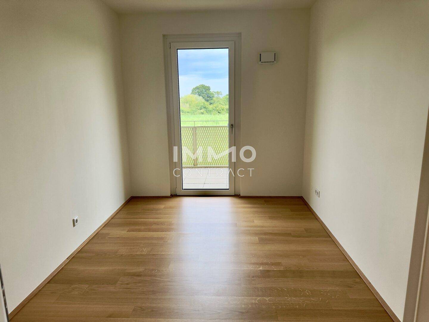 Helles Zimmer mit Holzboden und Zugang zu einem Außenbereich, ideal als Schlaf- oder Arbeitszimmer.