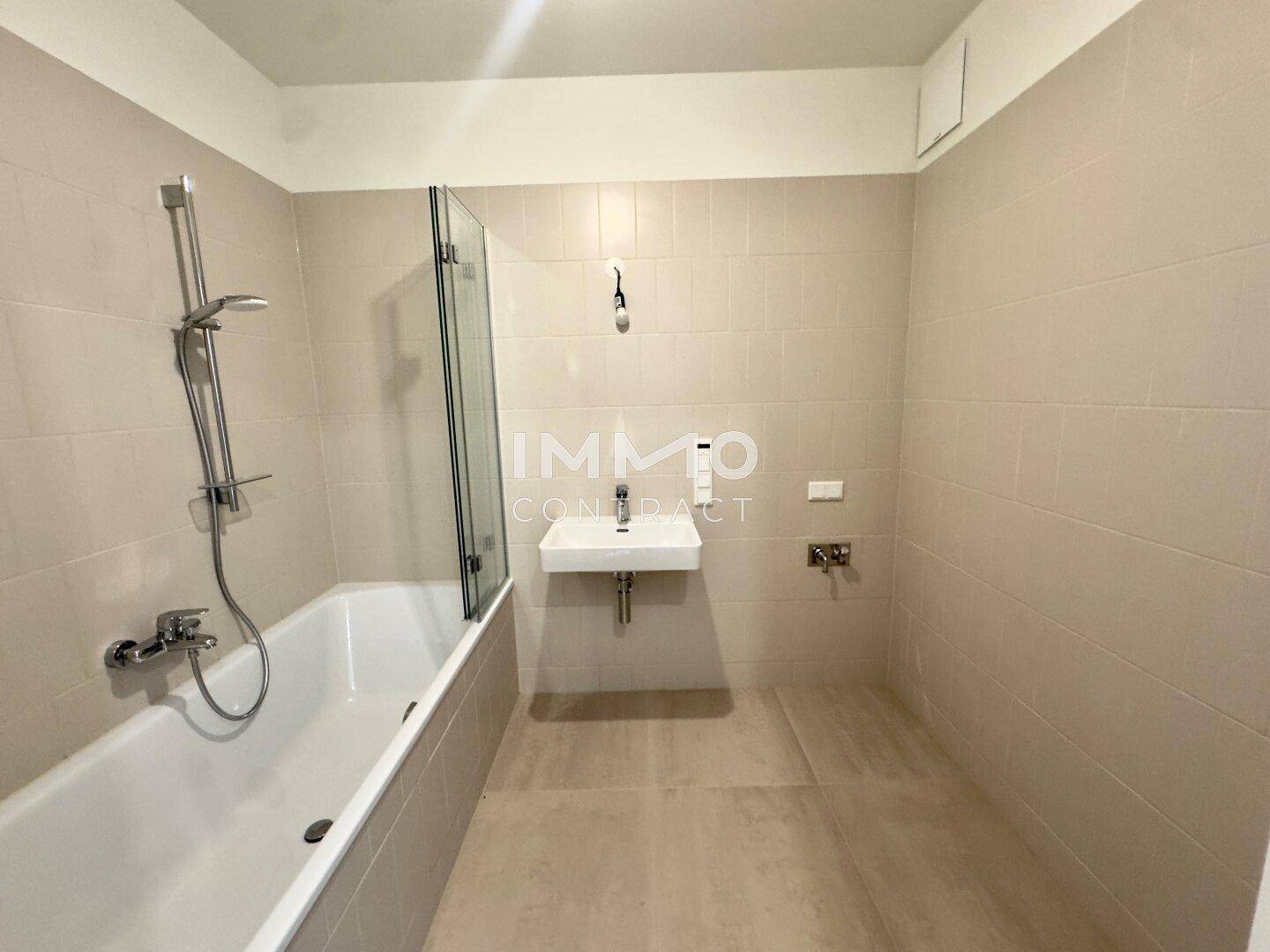 Modernes Badezimmer mit Badewanne, Duschfunktion und einem einzelnen Waschbecken, komplett gefliest.