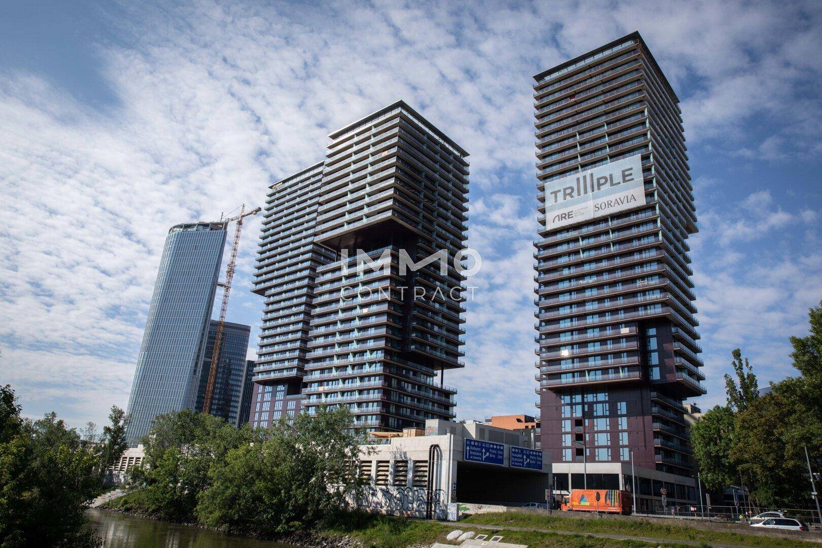 Moderne Hochhäuser mit markanter Architektur und Glasfassaden am Flussufer.