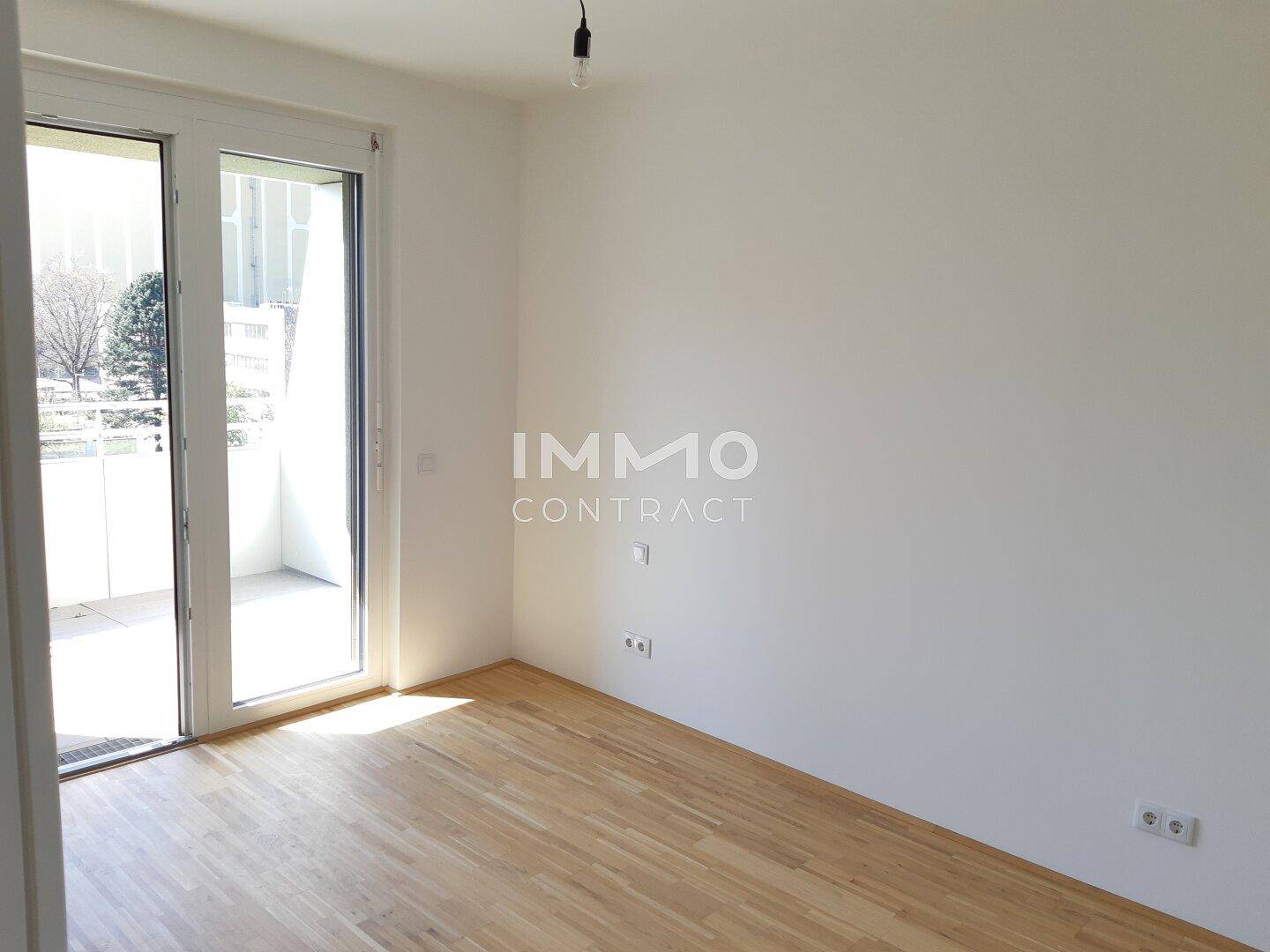 Heller Raum mit Holzboden und Zugang zu einem Balkon, ideal für verschiedene Nutzungen.