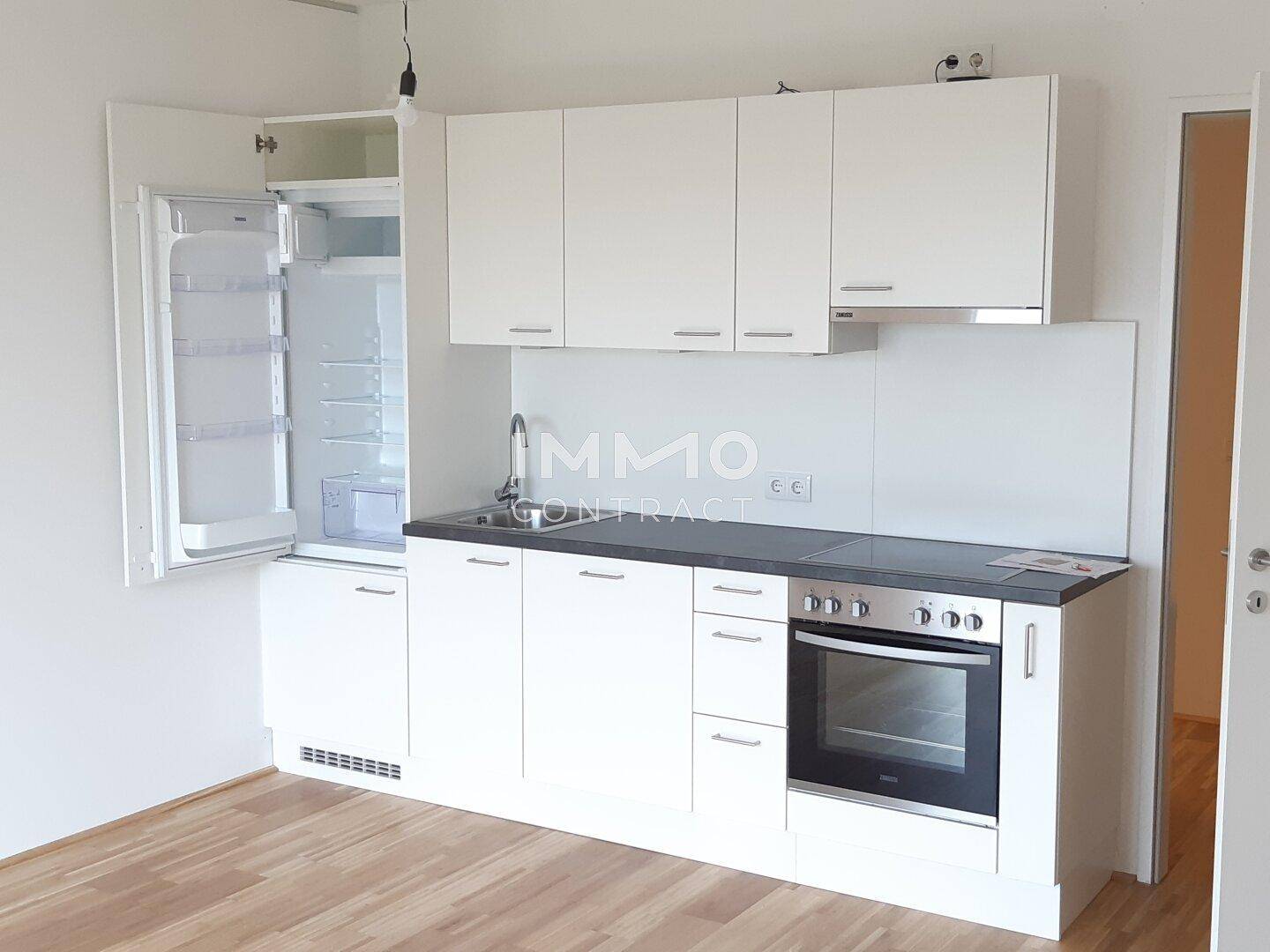 Kleine Einbauküche in Weiß mit integriertem Kühlschrank, Kochfeld und Backofen.