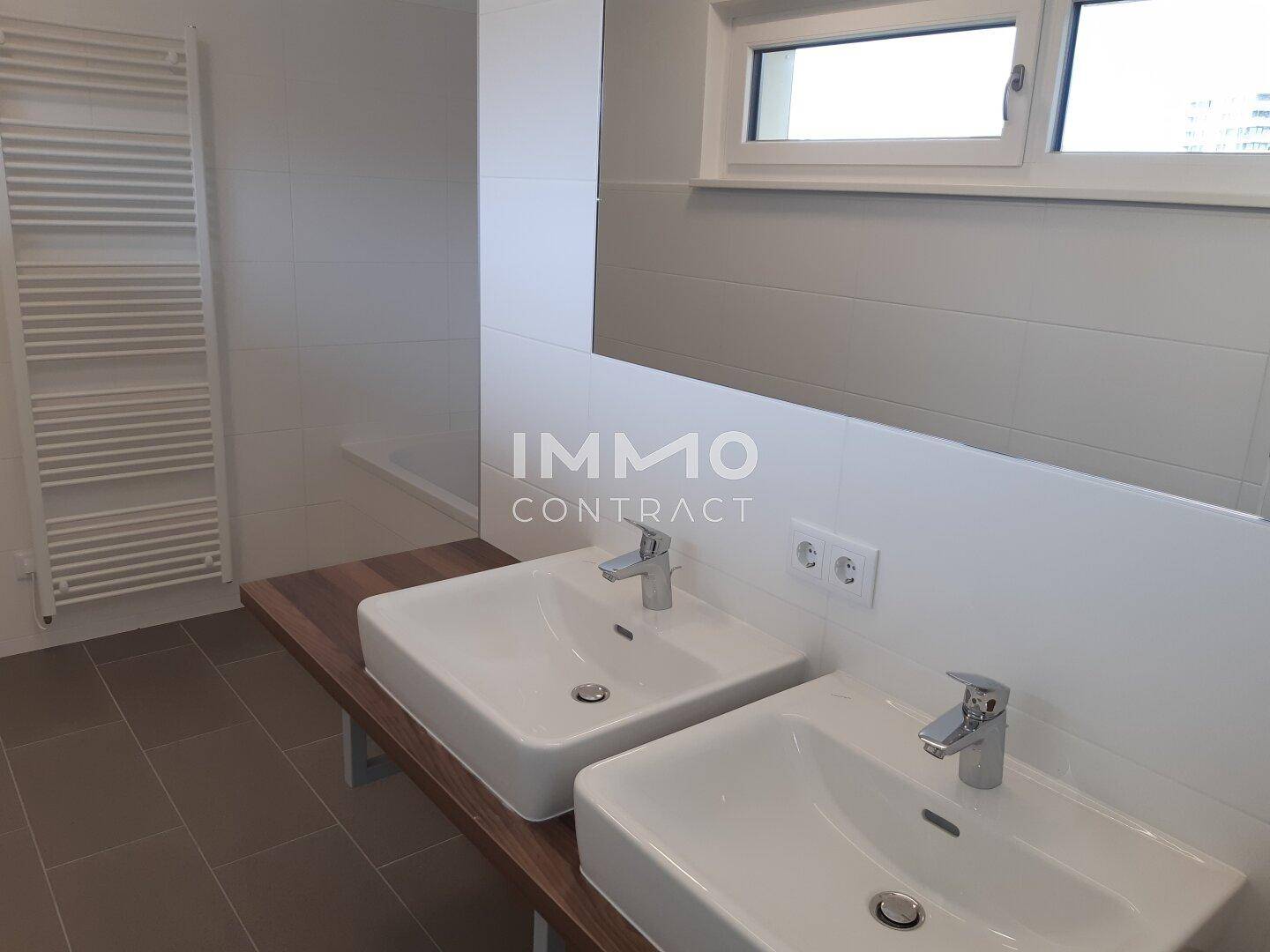 Modernes Badezimmer mit Doppelwaschbecken, Fenster und beheiztem Handtuchhalter.