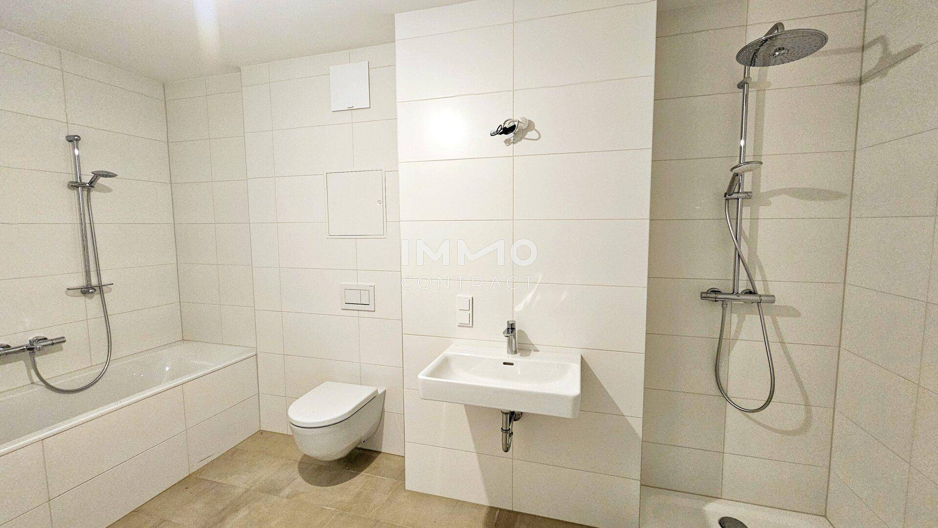Modernes Badezimmer mit Badewanne, Dusche, WC und weißen Fliesen.