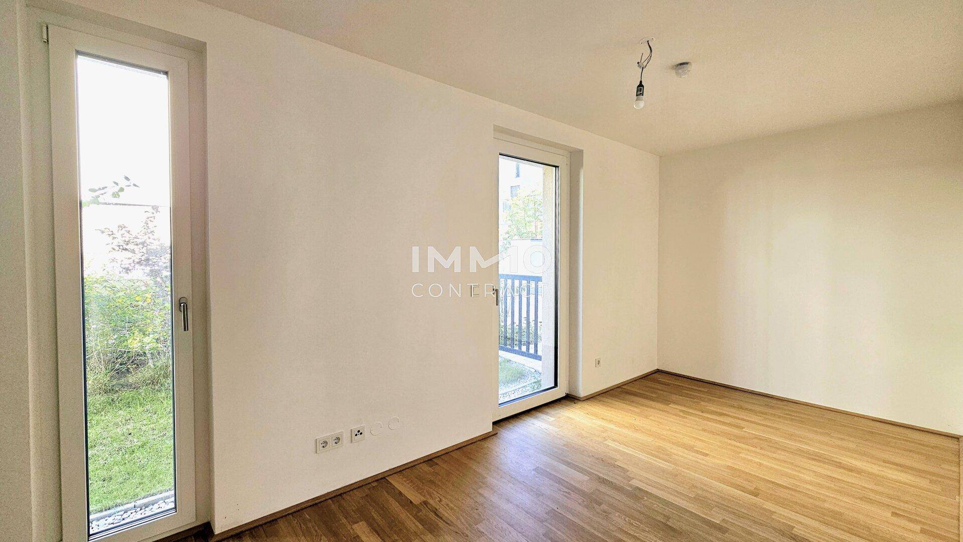 Helles Schlafzimmer mit Parkettboden und Zugang zu einem kleinen Balkon.