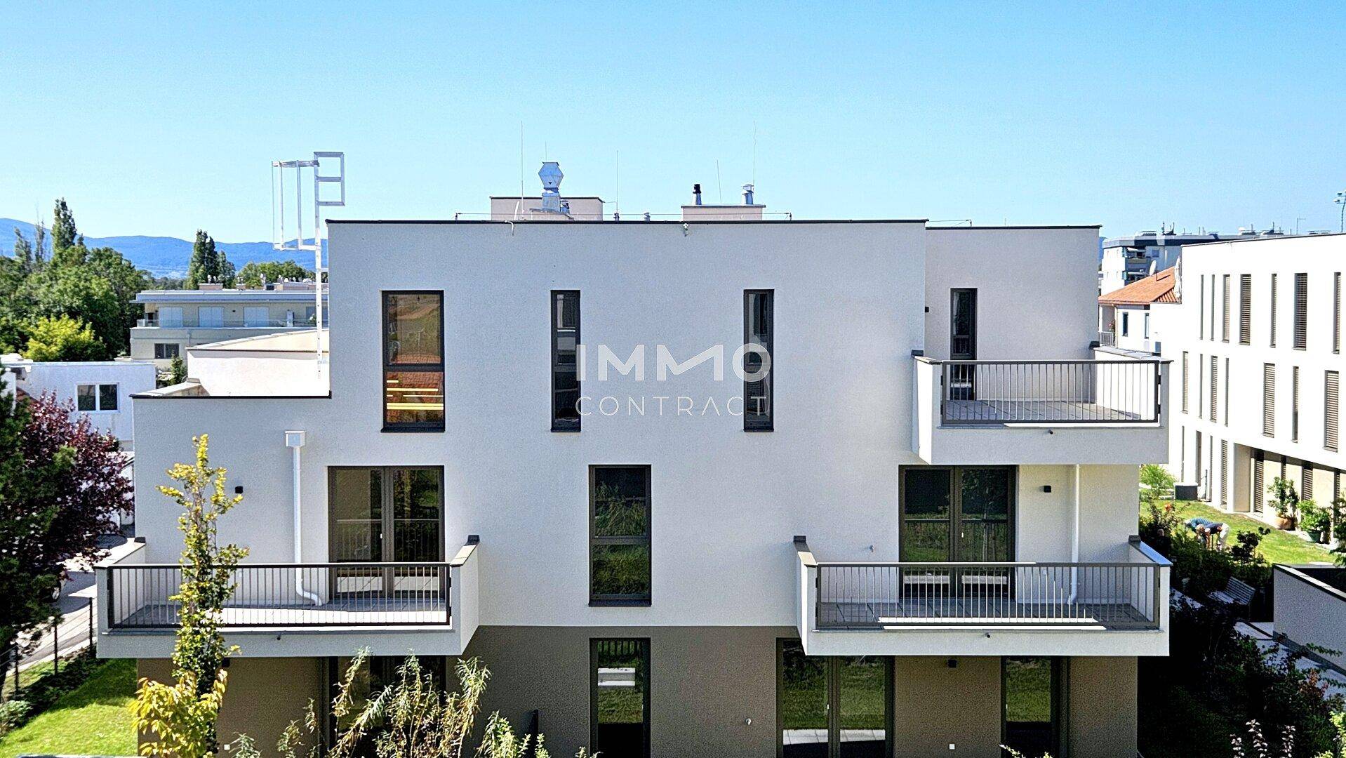 Moderne Wohngebäude mit Balkonen und großen Fenstern unter blauem Himmel.