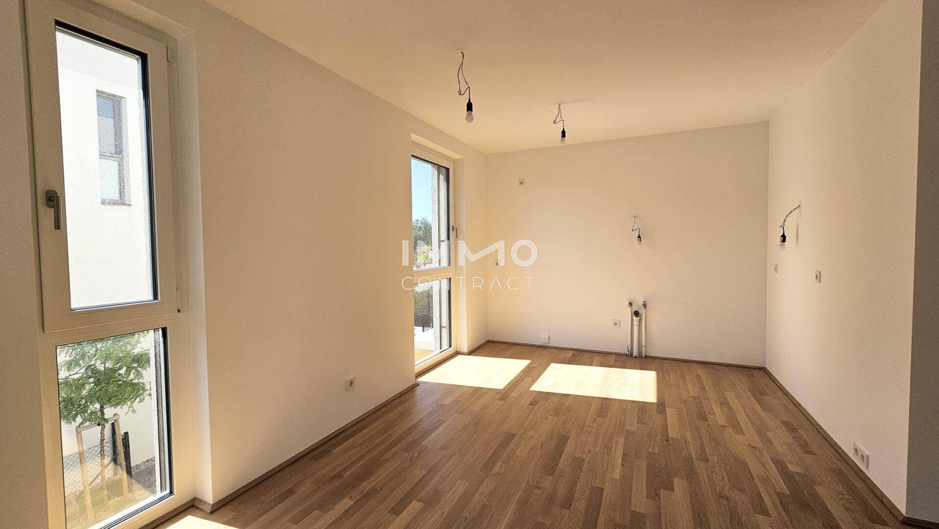 Lichtdurchfluteter Raum mit Holzboden und Zugang zu einem Außenbereich, ideal als Wohnzimmer.