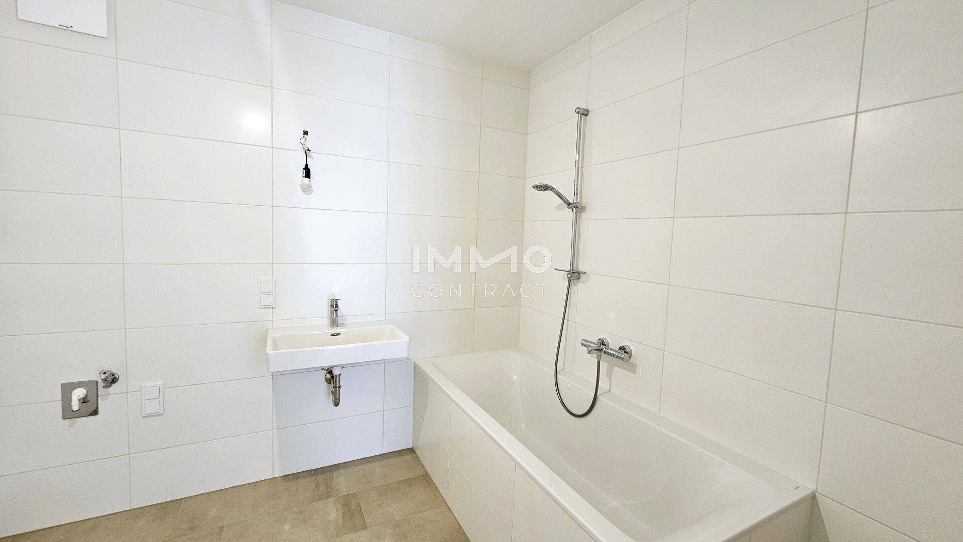 Modernes Badezimmer mit weißen Fliesen, Badewanne und einem einzelnen Waschbecken.