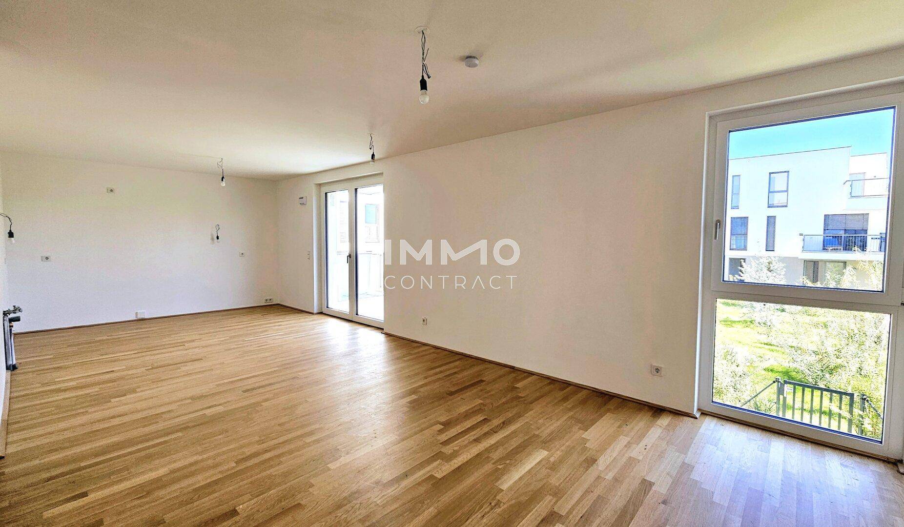 Geräumiges Wohnzimmer mit hellem Parkettboden und großen Fenstern zum Garten.