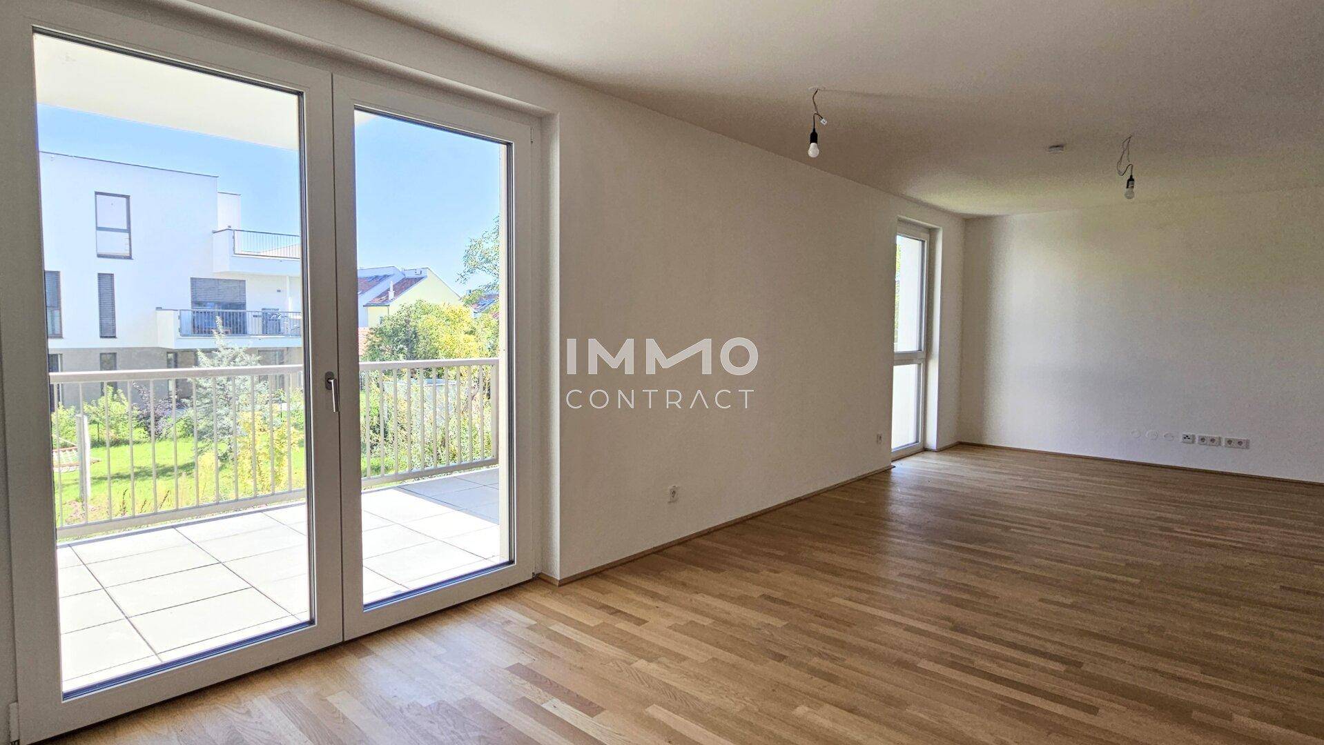 Helles Wohnzimmer mit Parkettboden und Zugang zu einem großzügigen Balkon.