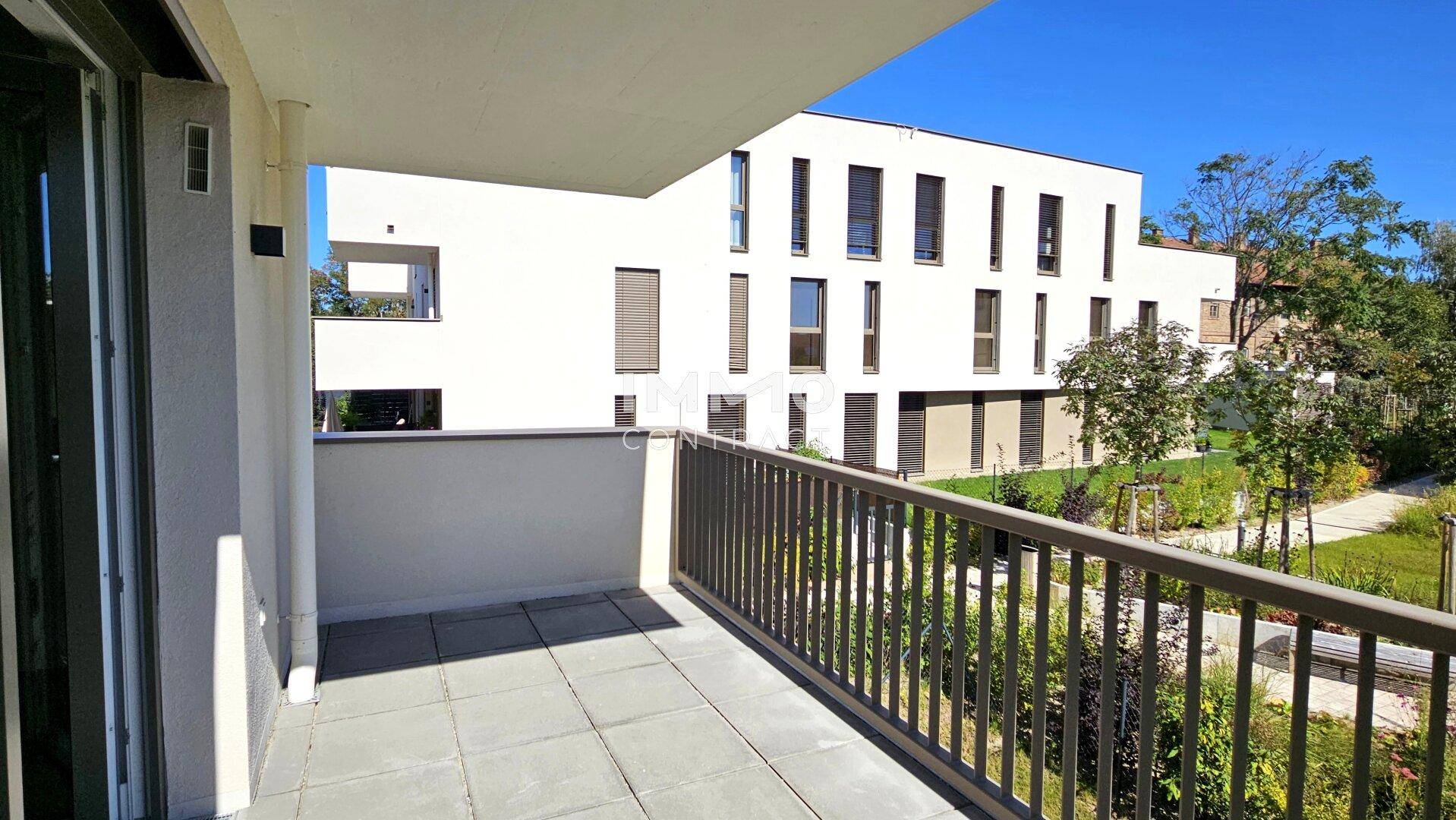 Geräumiger Balkon mit Fliesenboden und Blick auf die moderne Wohnanlage.