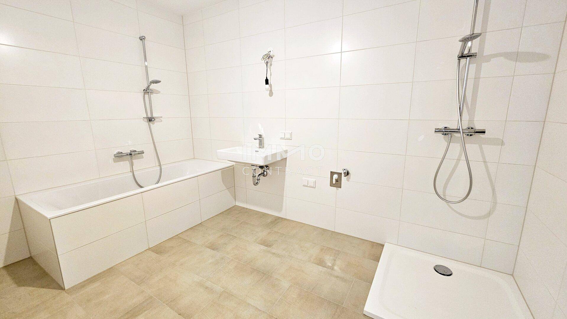 Modernes Badezimmer mit Badewanne, Dusche und weißen Fliesen.
