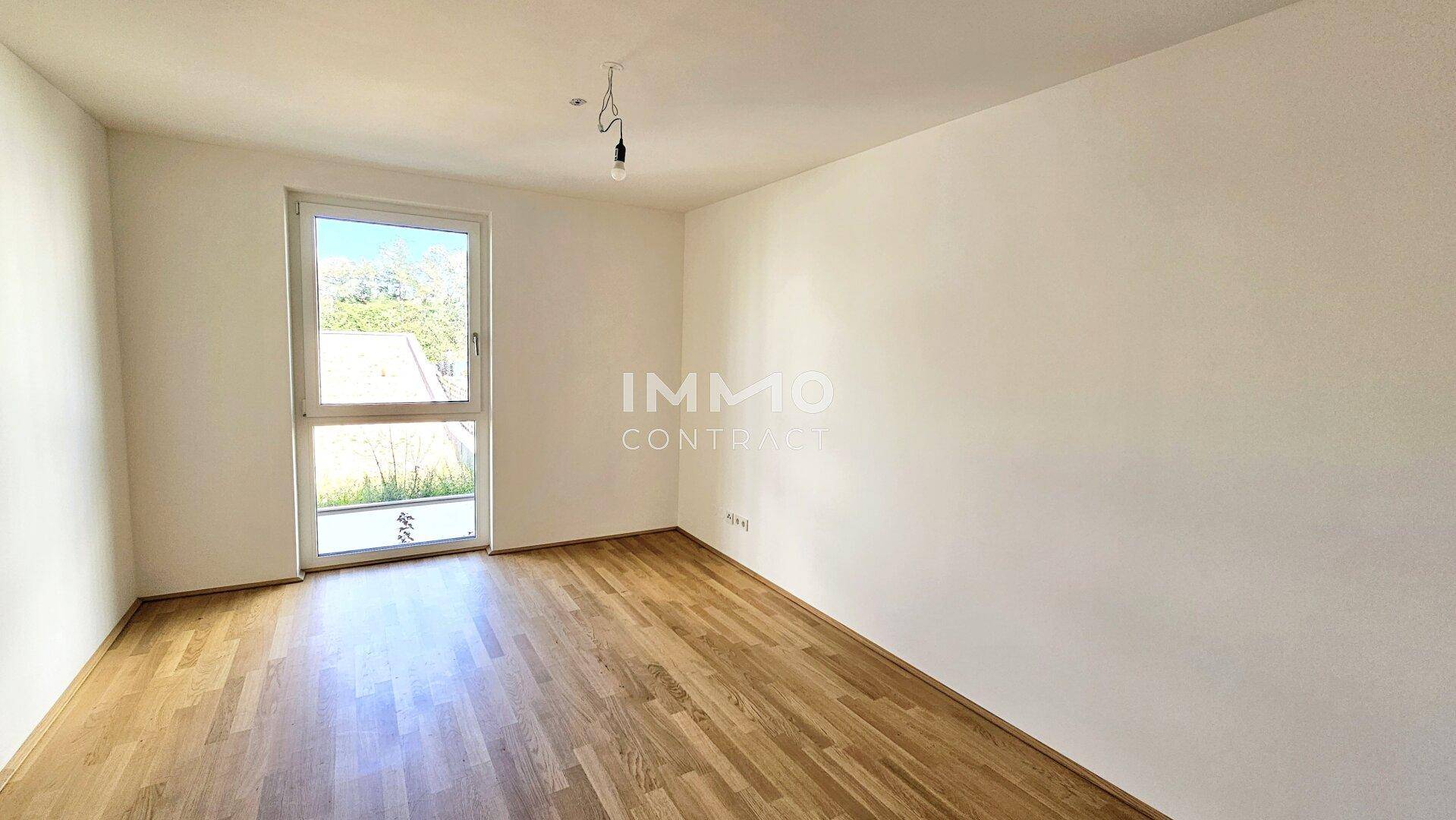 Geräumiges Schlafzimmer mit Parkettboden und einem Fenster, das viel Licht hereinlässt.
