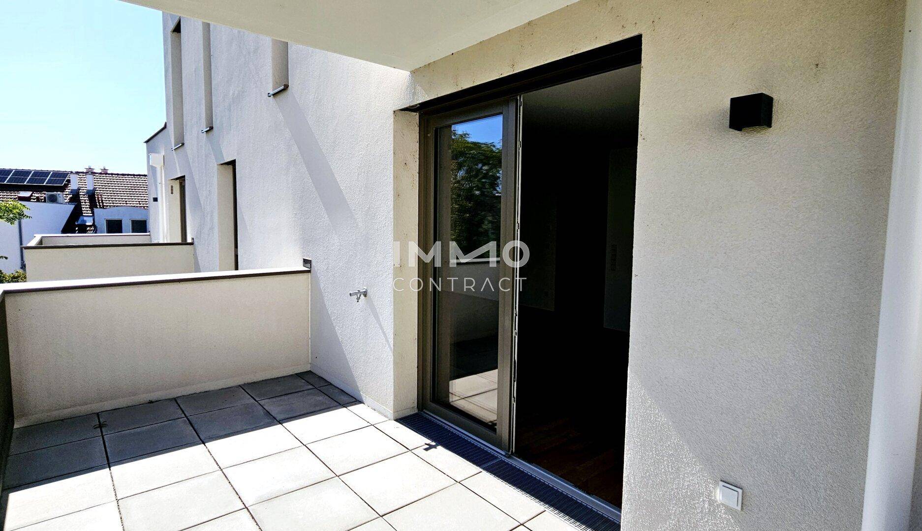 Heller Balkon mit Fliesenboden und Schiebetür, ideal für entspannte Stunden im Freien.