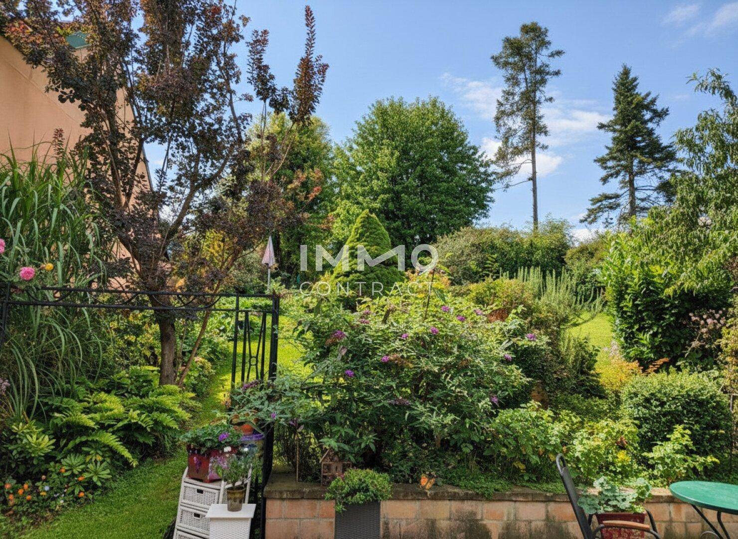 Üppiger, grüner Garten mit vielfältiger Bepflanzung, hohen Bäumen und einem kleinen Zaun, ideal zum Entspannen.