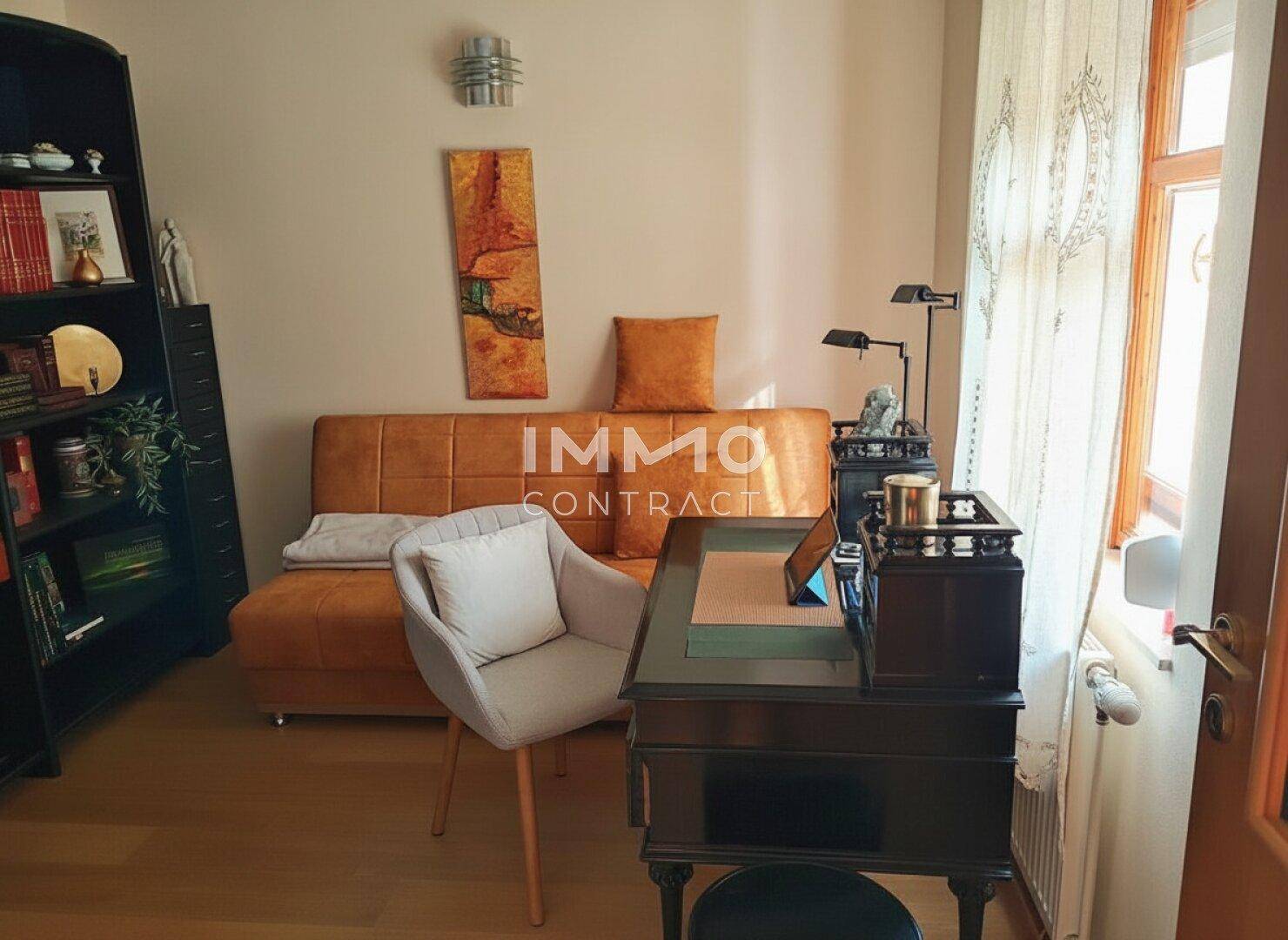 Ruhiges Arbeitszimmer mit einem klassischen Schreibtisch, einem bequemen Sessel und einem Sofa, ideal zum Arbeiten.