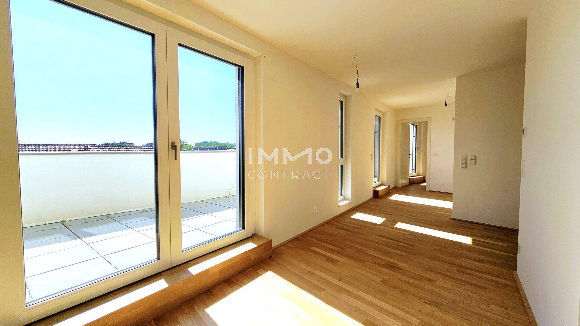 Geräumiges Zimmer mit Holzboden, viel Tageslicht und Zugang zur Außenterrasse.