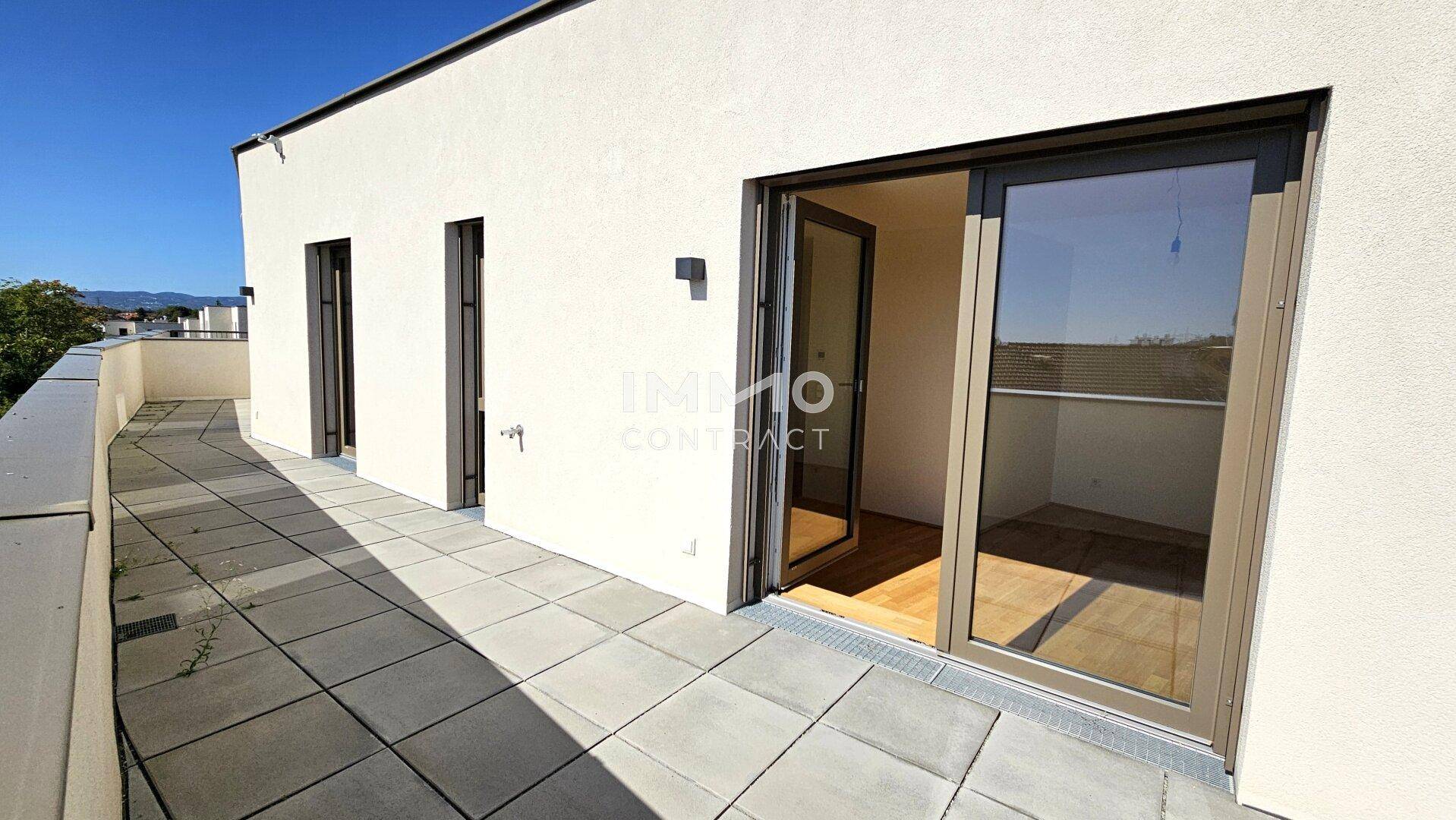 Große, geflieste Terrasse mit Schiebetüren, die in den Innenbereich führen.