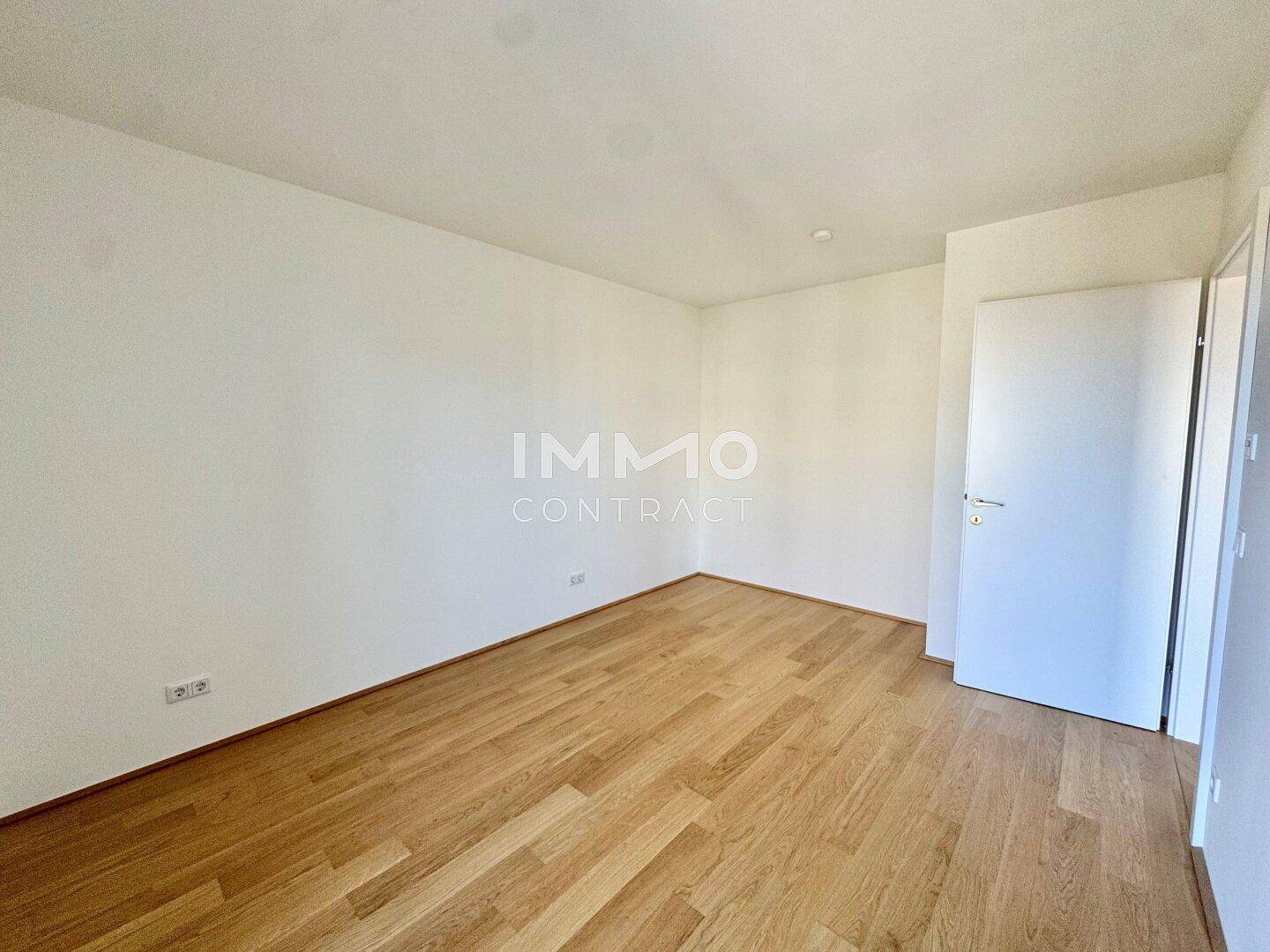 Leeres Zimmer mit hellem Parkettboden und weißen Wänden, ideal als Schlafzimmer.
