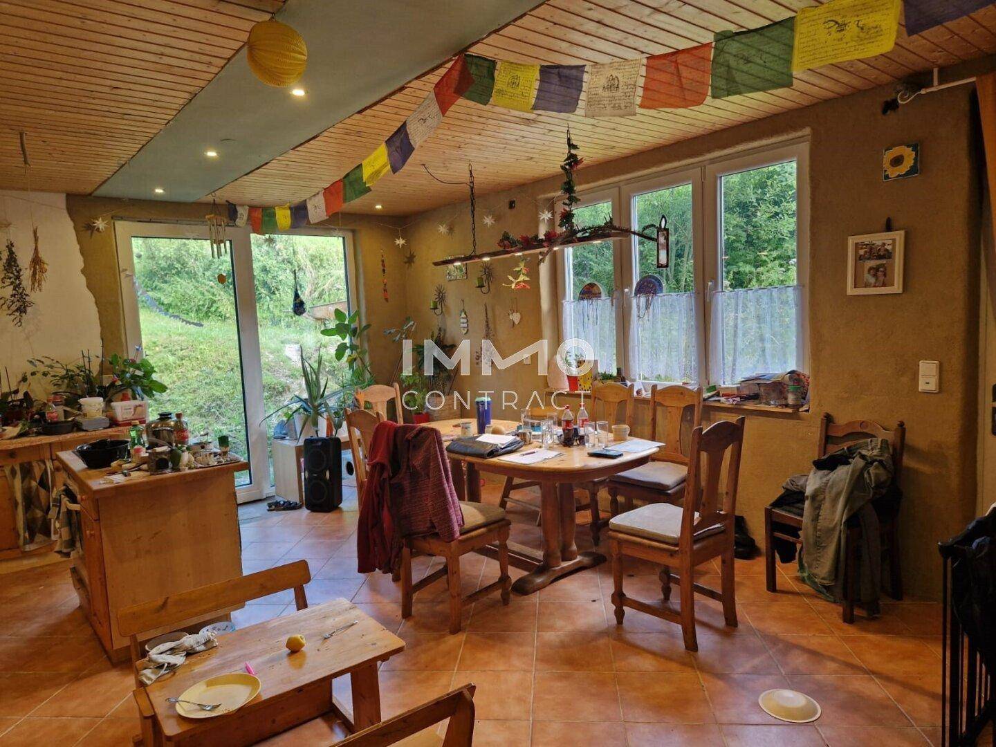 Rustikaler Essbereich mit Holztisch, bunten Dekorationen und Zugang zum Garten.