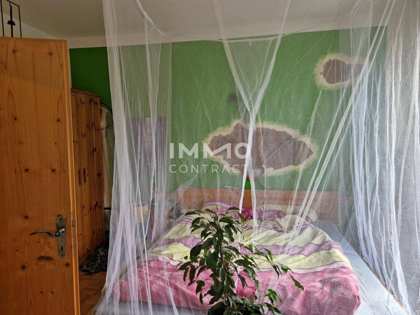Schlafzimmer mit grün gestrichenen Wänden, Holzbett und Moskitonetz.