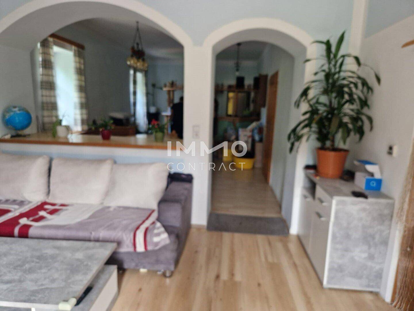 Heller Wohnbereich mit Holzboden, Sofa und dekorativen Bögen.