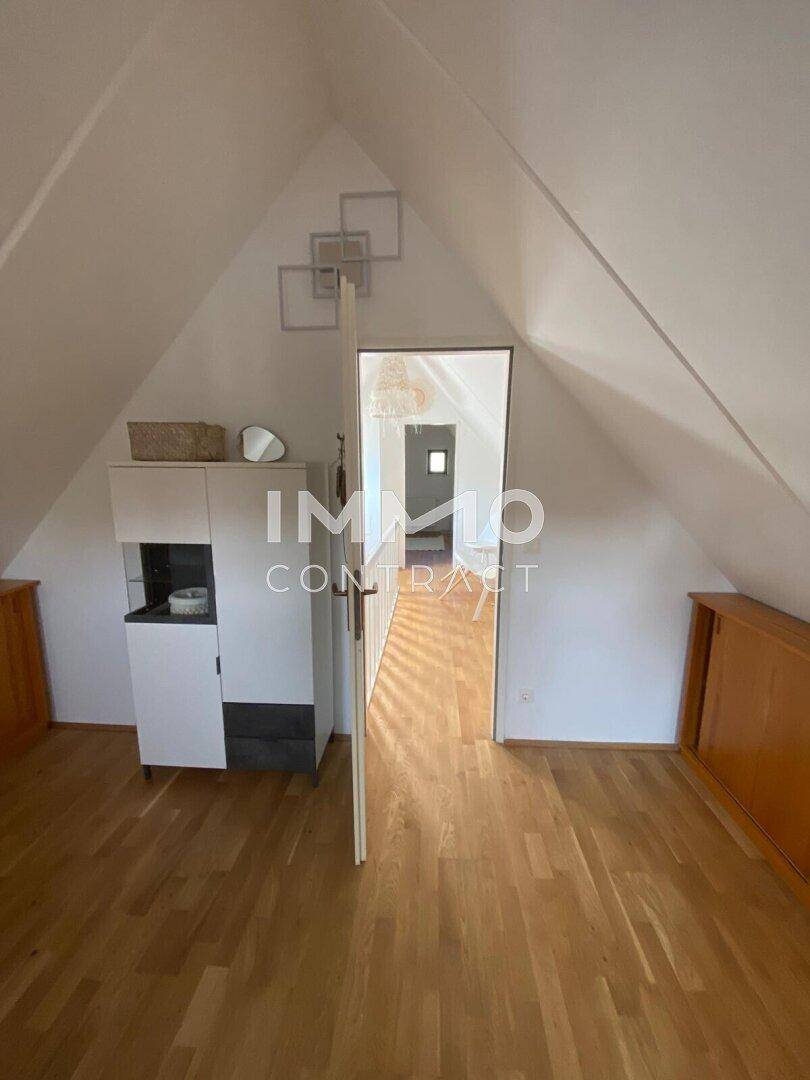 Geräumiges Schlafzimmer im Dachgeschoss mit Holzboden, Dachschräge und weißem Schrank.