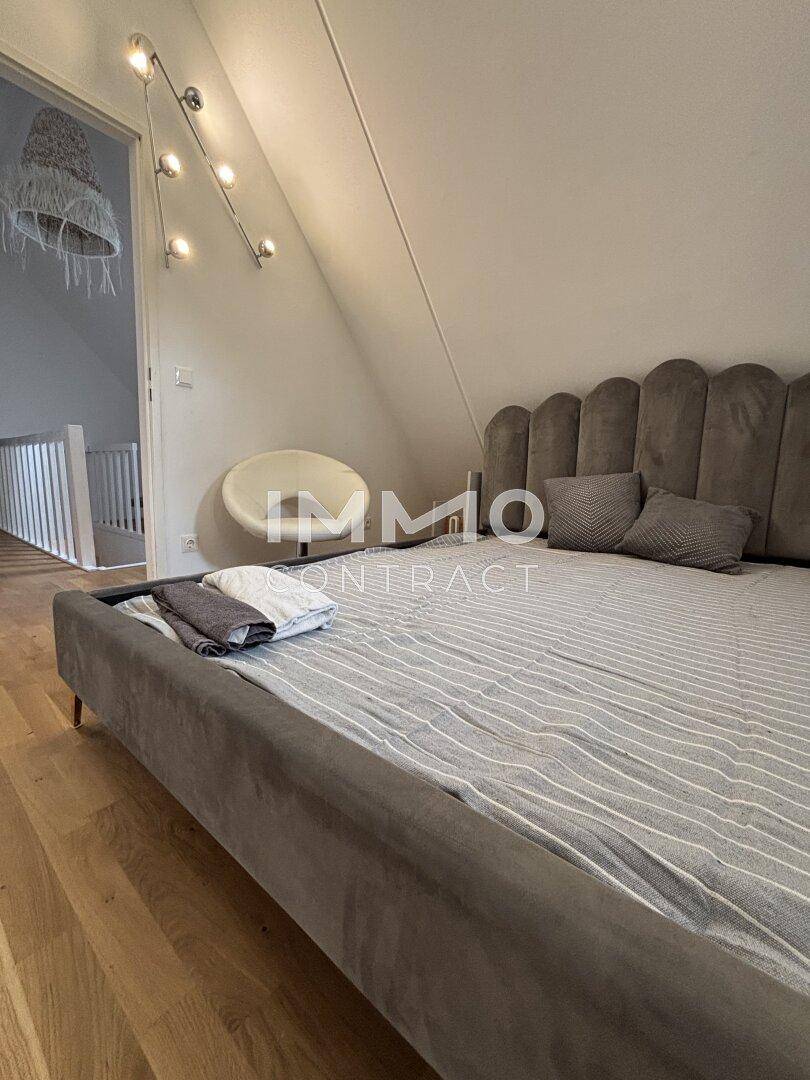 Gemütliches Schlafzimmer im Dachgeschoss mit modernem Bett, Holzboden und Dachschräge.