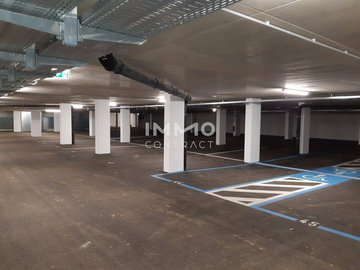 Geräumige Tiefgarage mit markierten Parkplätzen und Beleuchtung, inklusive Behindertenparkplatz.