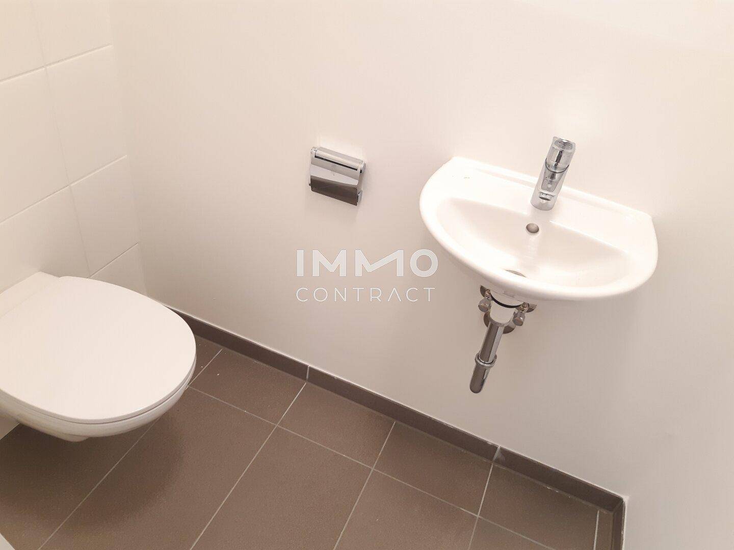 Kompakte Gästetoilette mit Wand-WC und kleinem Handwaschbecken in neutralen Farben.