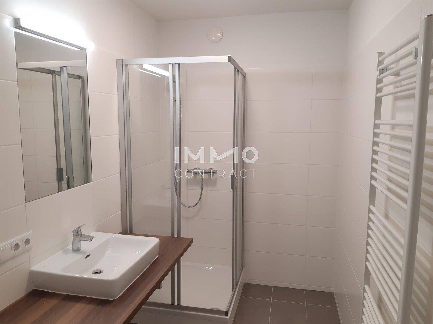 Modernes Badezimmer mit Duschkabine, Waschbecken und beheiztem Handtuchhalter in Weiß.