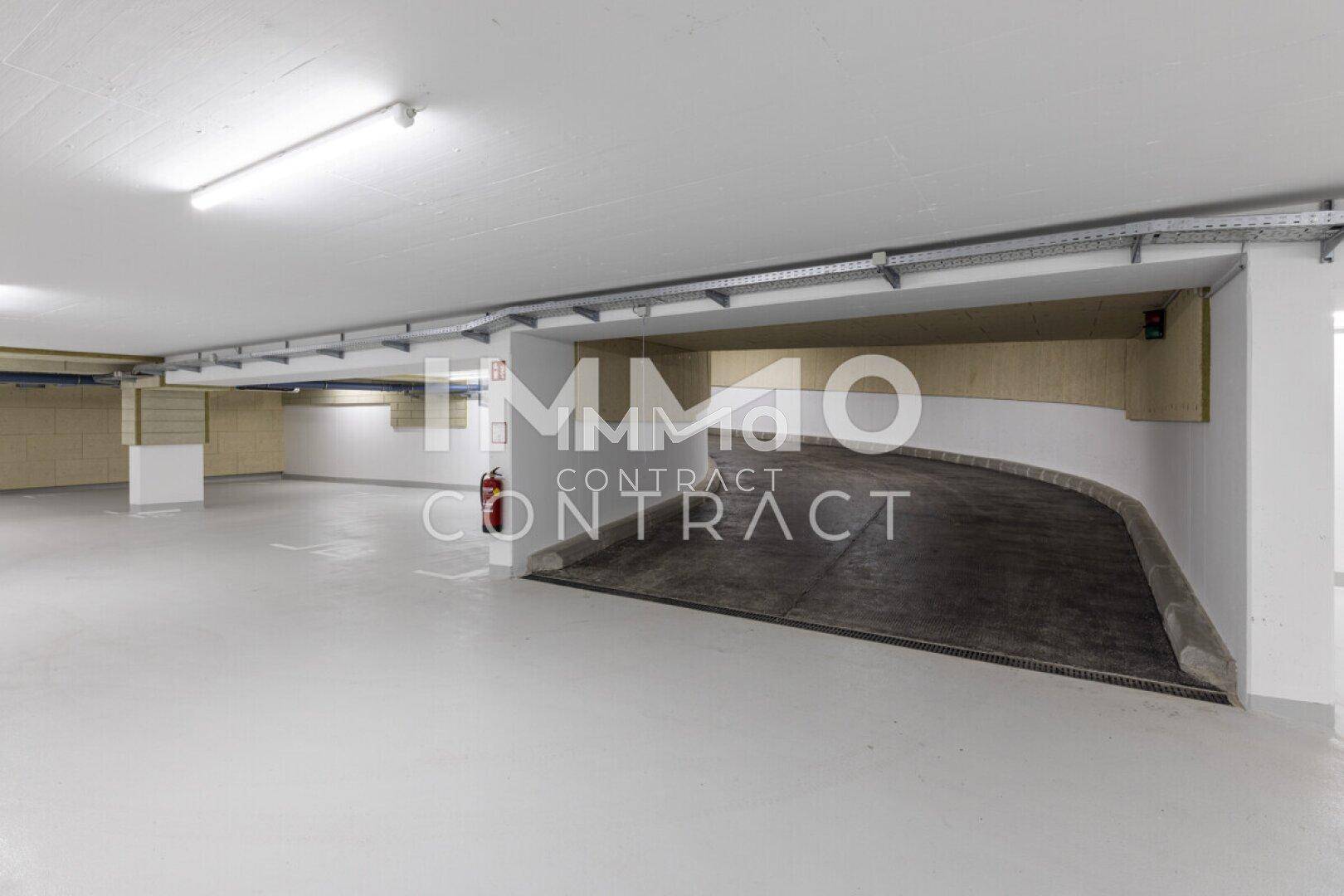 Geräumige Tiefgarage mit heller Beleuchtung und einer Rampe für Fahrzeuge.