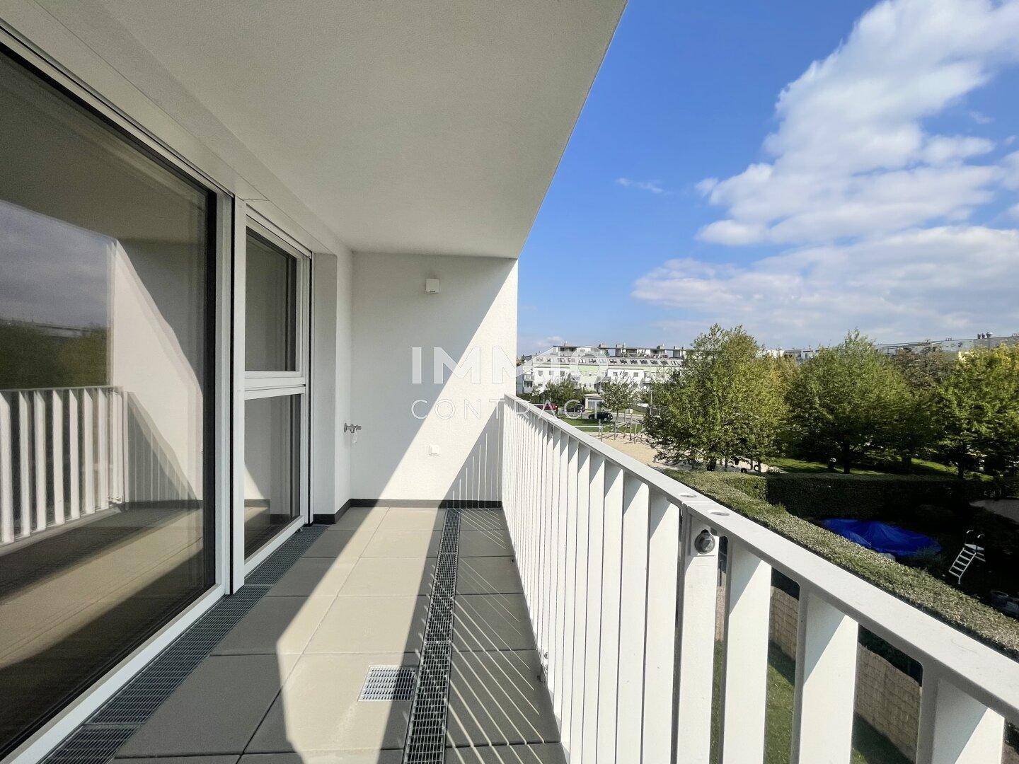 Geräumiger Balkon mit Fliesenboden und Blick auf grüne Bäume und die Umgebung.